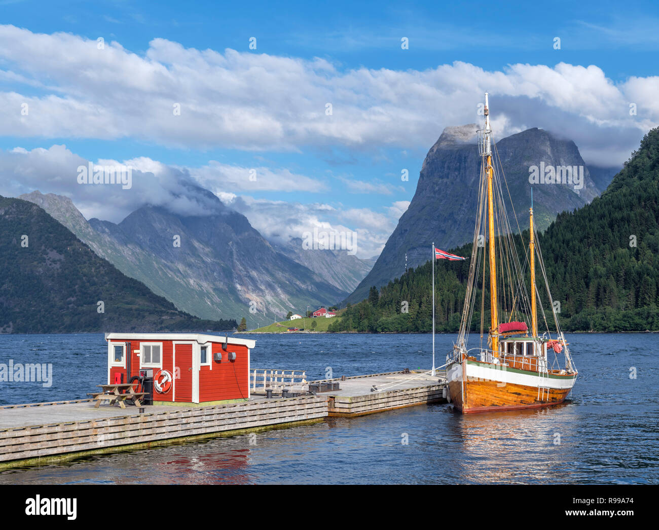 Fiordi Norvegesi. Tradizionale imbarcazione attraccata ad un molo al di fuori il Sagafjord hotel nel tardo pomeriggio, Saebø, Hjørundfjorden, Møre og Romsdal, Norvegia Foto Stock