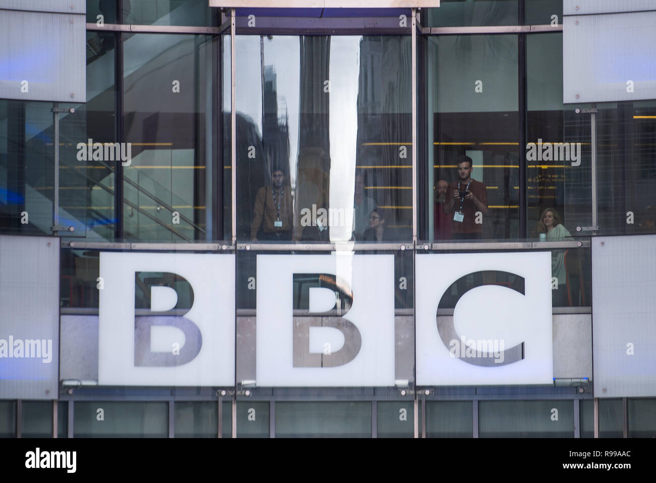 Lo staff di BBC guarda da windows durante una manifestazione di protesta dalla ribellione di estinzione al di fuori del gruppo della BBC Broadcasting House di Londra, durante una manifestazione di protesta contro il loro modo di pensare l'emittente copre il "Emergenza climatica". Foto Stock