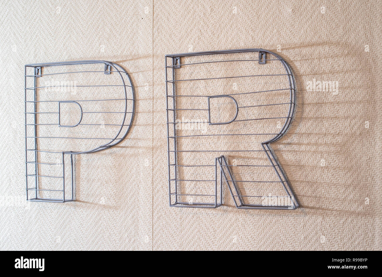 PR parola sulla parete. Relazioni pubbliche nozione con 3D lettere PR in pietra. Foto Stock