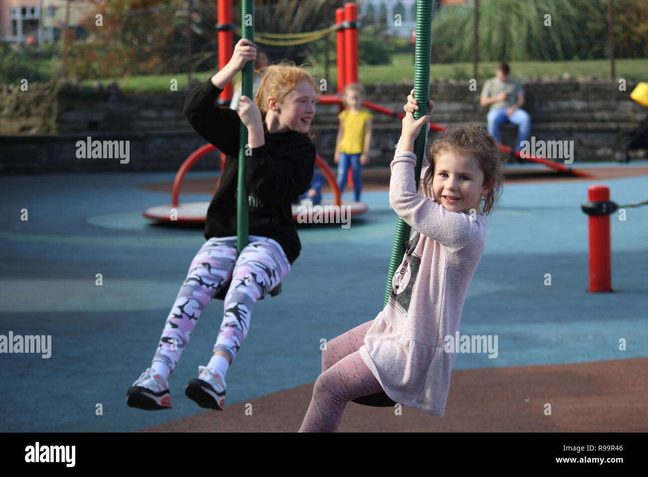 due sorelle bambini che giocano in una doppia altalena nel parco solare di skegness Foto Stock
