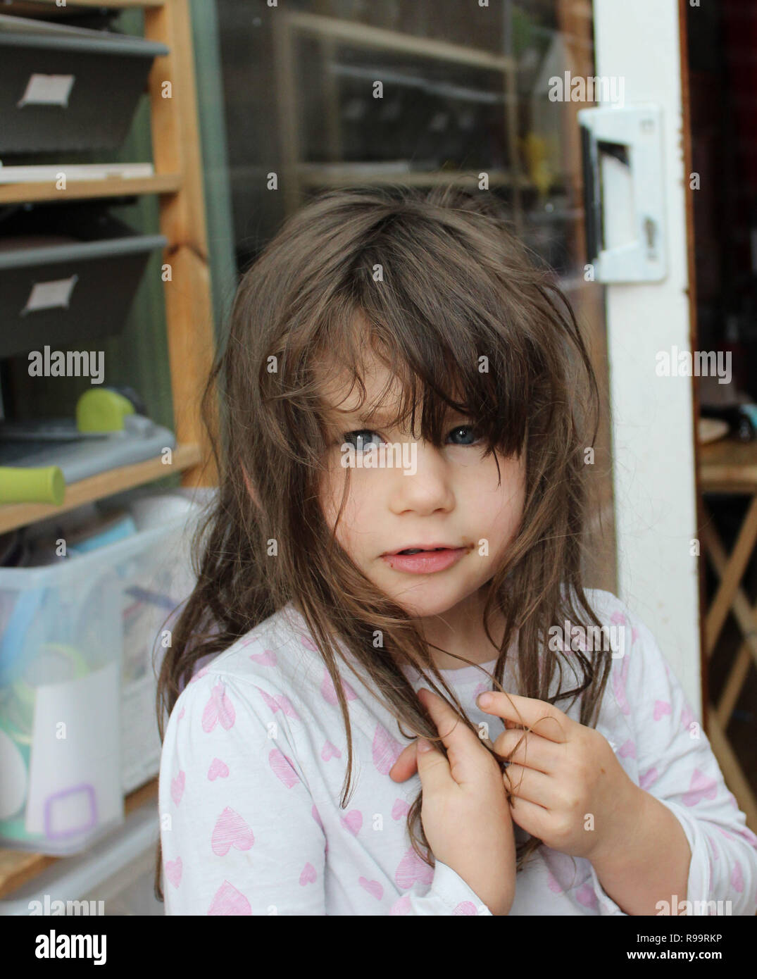 Giovane Brunette ragazza con capelli marroni sudati nei suoi pigiami e cioccolato intorno alla bocca Foto Stock