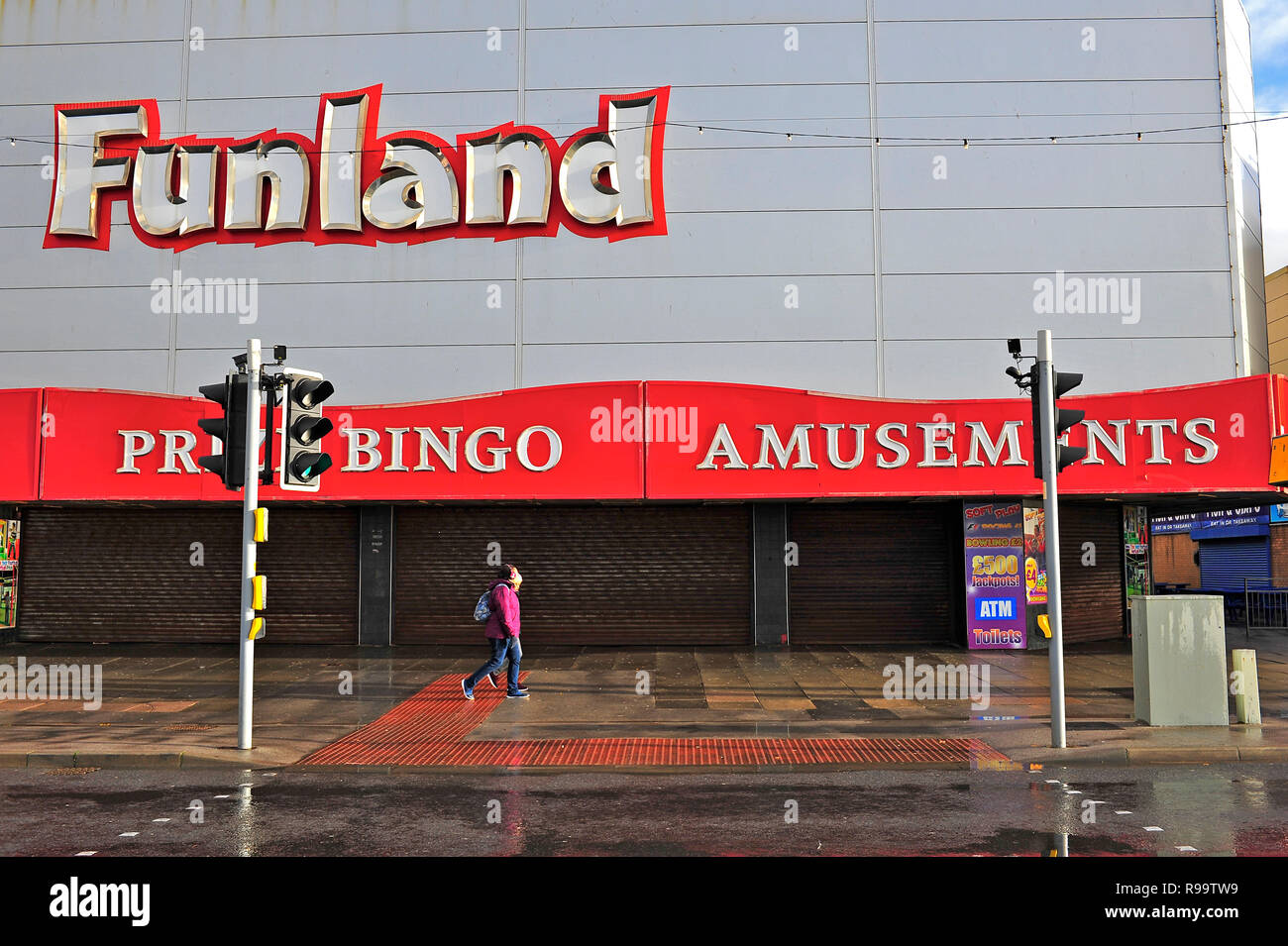 Due persone a piedi lungo la passeggiata di fronte ad una chiusa Funland sala giochi in un giorno di pioggia in inverno in Blackpool Foto Stock