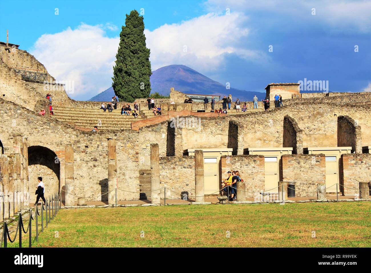 Pompei, Italia - 23 Ottobre 2018: turisti esplorare i resti dell'anfiteatro in antiche città di Pompei, con il Monte Vesuvio a distanza Foto Stock