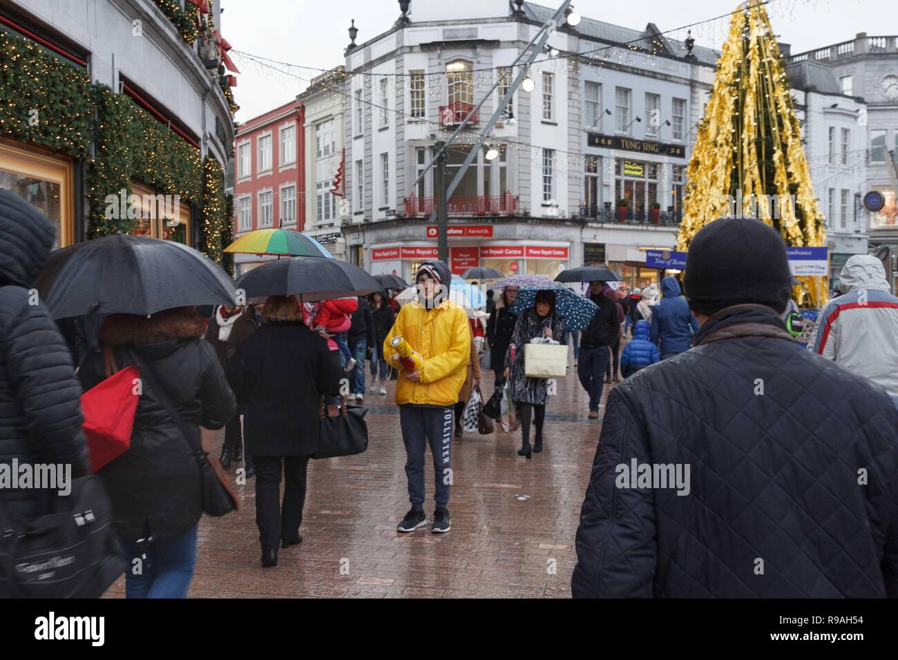 Cork, Irlanda, 21 dicembre, 2018. Acquazzoni Dont dissuadere gli acquirenti su ultimo venerdì prima di Natale, la città di Cork. La pioggia che è caduta per tutto il giorno non volevo interrompere gli acquirenti di ottenere il loro finale di pochi bit e pezzi in città sul finale il fine settimana prima di Natale. Le strade erano piene di acquirenti correre da un negozio all'altro evitando la pioggia, aswell come molte persone per raccogliere per beneficenza come condividere e sughero Simon. Credito: Damian Coleman/Alamy Live News. Foto Stock