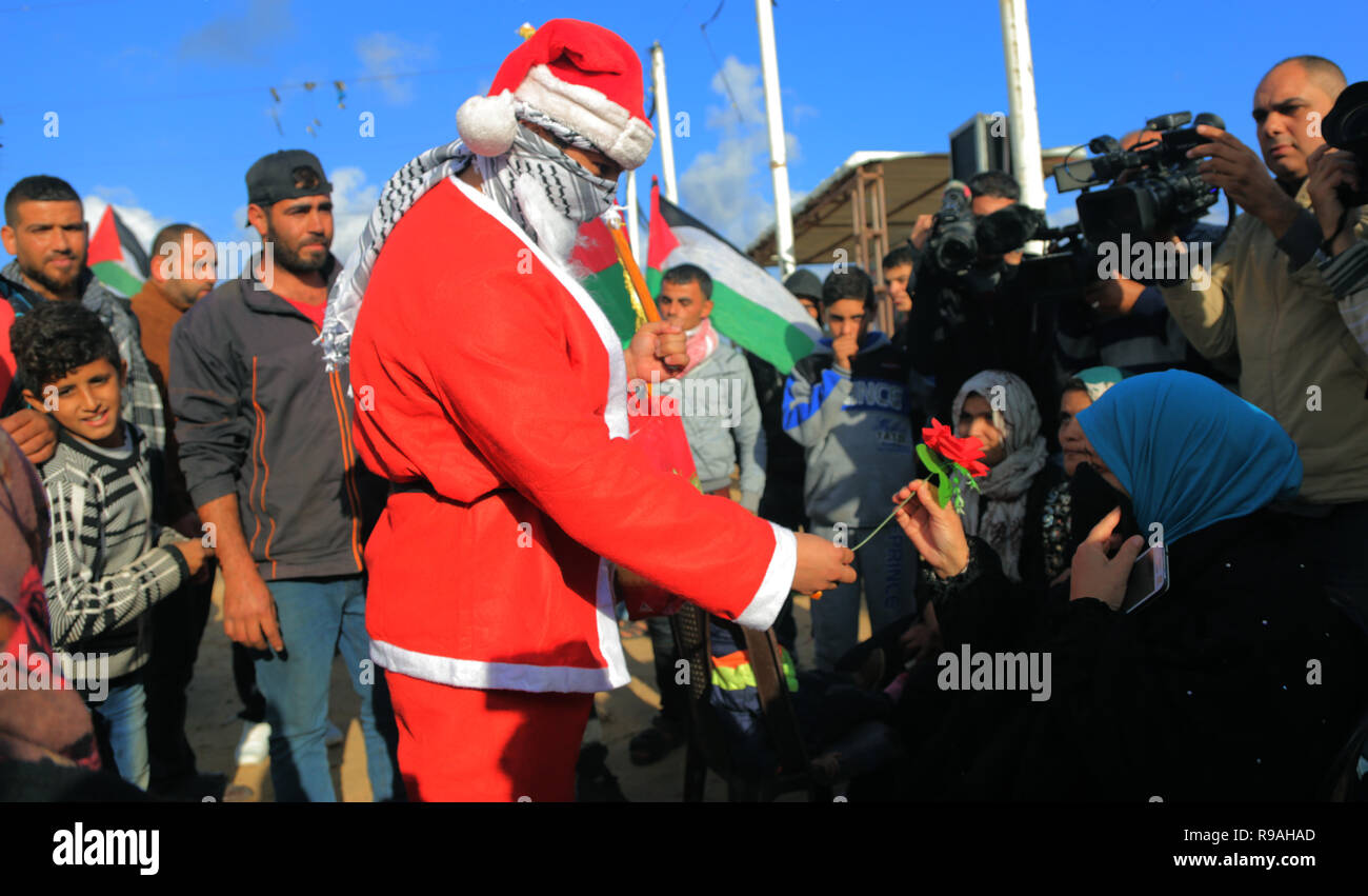 Khan Yunis, Gaza, Territori palestinesi. 21 dic 2018. Palestina - un palestinese visto indossare Babbo Natale vestiti distribuzione di fiori alle persone sul confine orientale di Khan Younis durante il Natale la stagione festiva. Credito: ZUMA Press, Inc./Alamy Live News Foto Stock