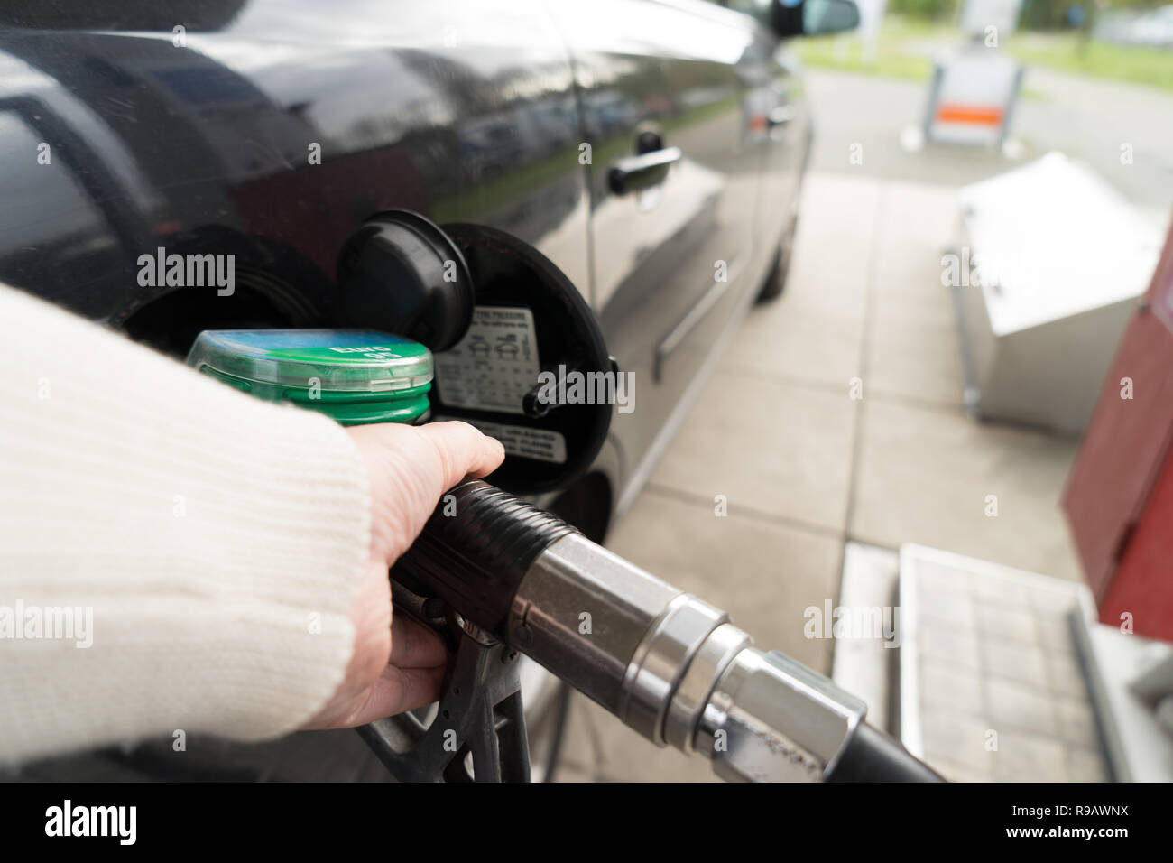 Femmina lato riempire la benzina in un auto con gas ugello della pompa Foto Stock