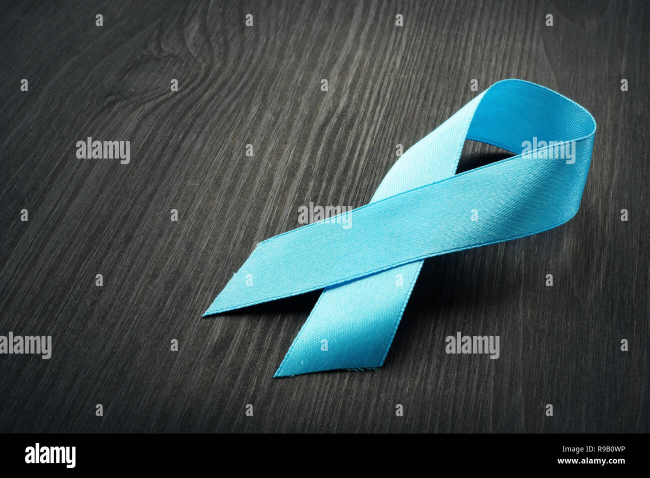 Blue Ribbon di sensibilizzazione su una scrivania nera. Il cancro della prostata. Foto Stock