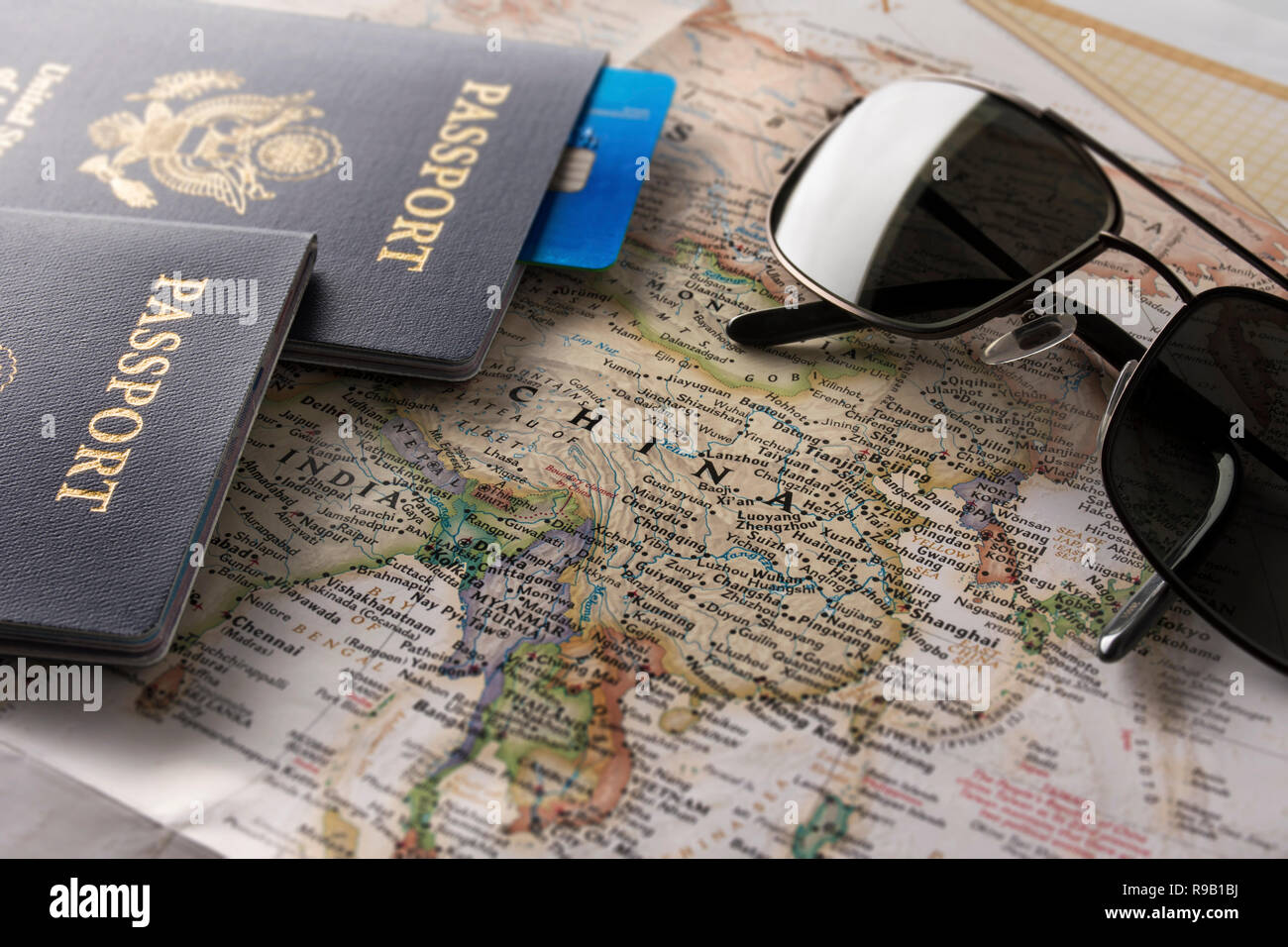 Primo piano di una mappa del mondo dotate per la maggior parte in Asia con i passaporti e una carta di credito in cima, più angolata. Foto Stock