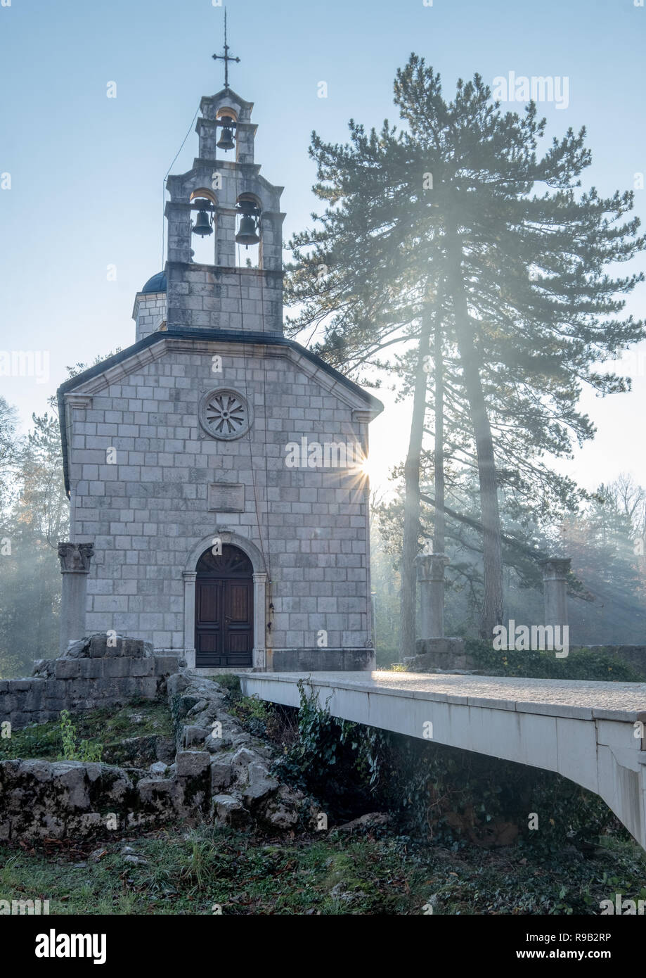 I cristiani ortodossi Chiesa di Corte Cipur a Cetinje. Mattina con la nebbia e il gelo, con raggio di sole raggiante verso la chiesa e ad albero e una raffica di Sun Foto Stock