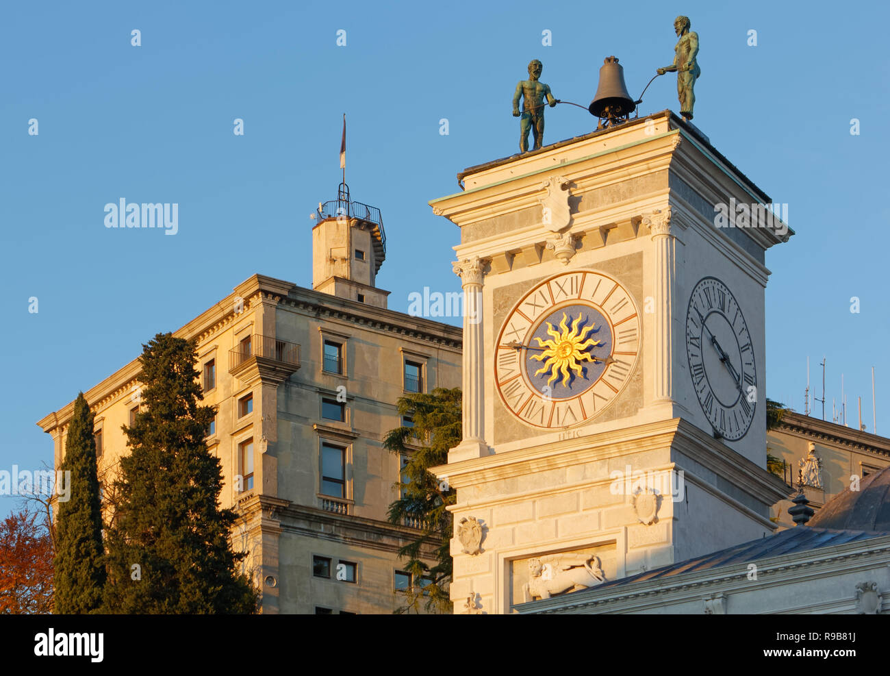 La Torre dell Orologio e il castello in background durante un tramonto in inverno a Udine, Italia Foto Stock