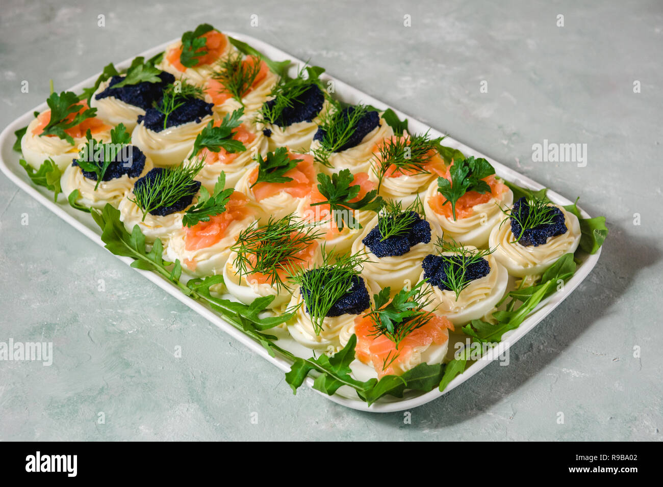 Uova ripiene con salmone e caviale decorate con il prezzemolo e l'aneto. Piatti per le feste Foto Stock