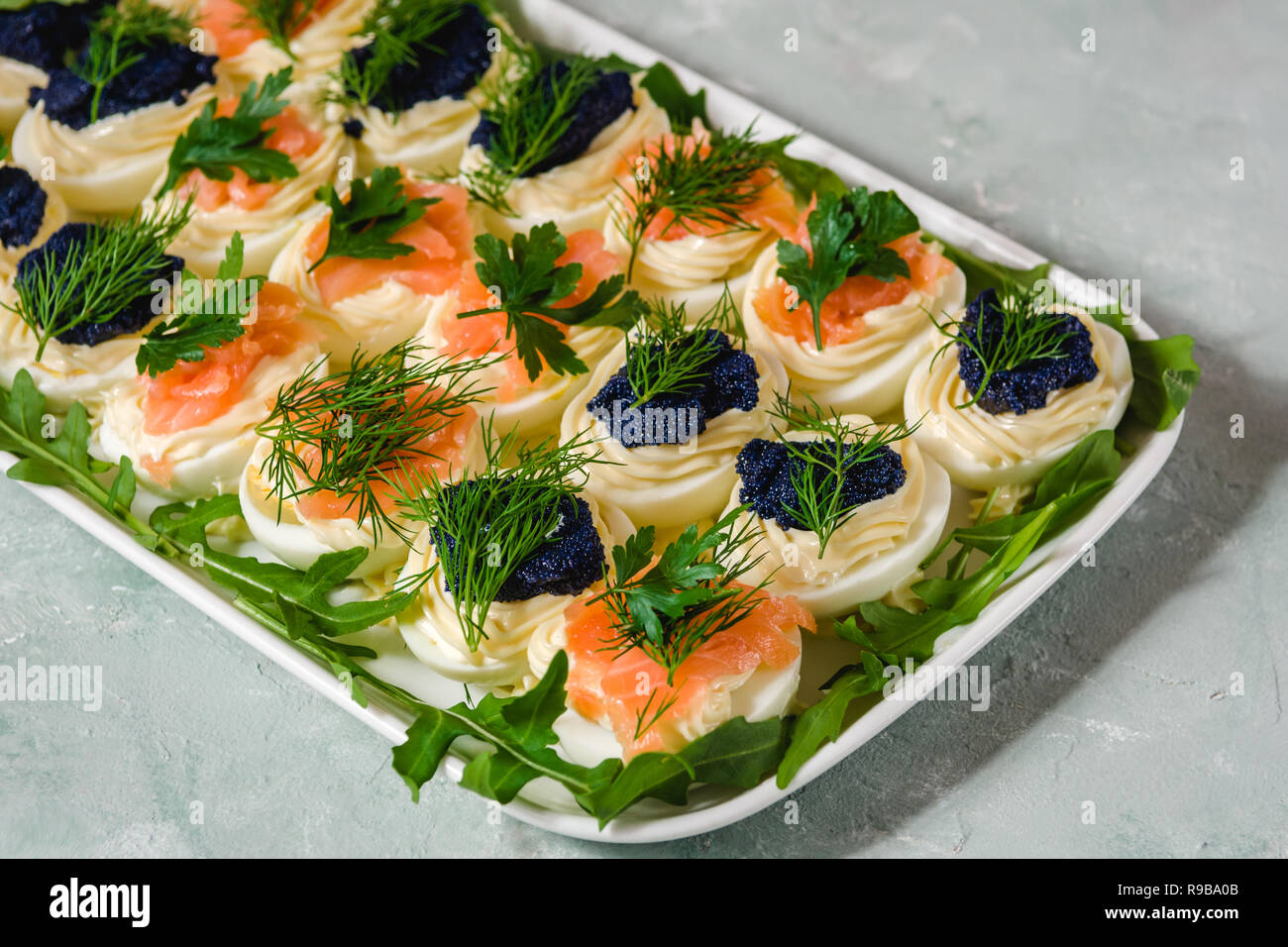 Uova ripiene con salmone e caviale decorate con il prezzemolo e l'aneto. Piatti per le feste Foto Stock
