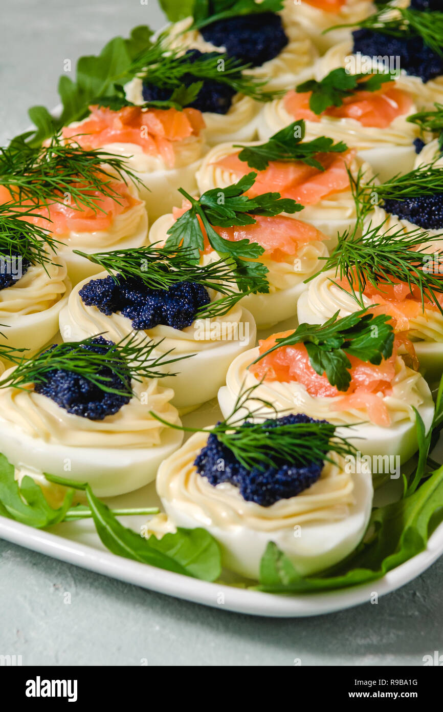 Uova ripiene con salmone e caviale decorate con il prezzemolo e l'aneto. Piatti per le feste Foto Stock