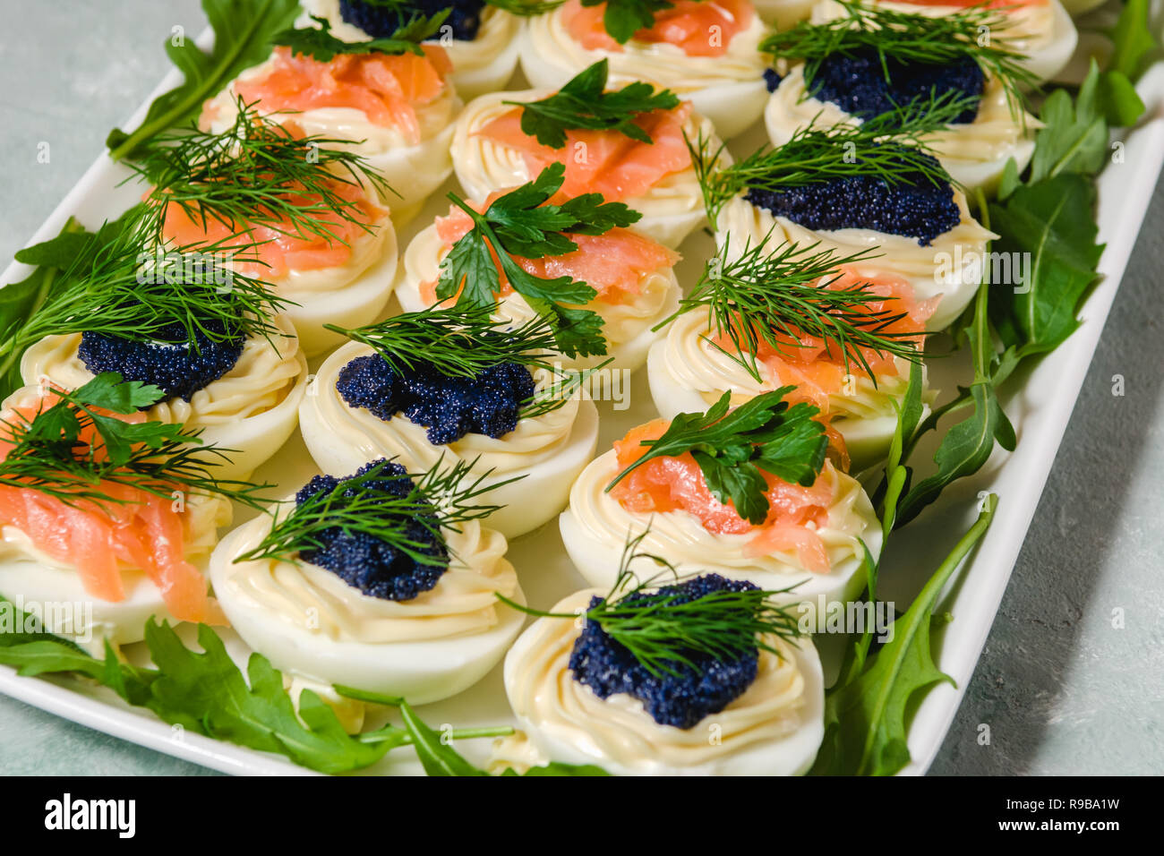 Uova ripiene con salmone e caviale decorate con il prezzemolo e l'aneto. Piatti per le feste Foto Stock