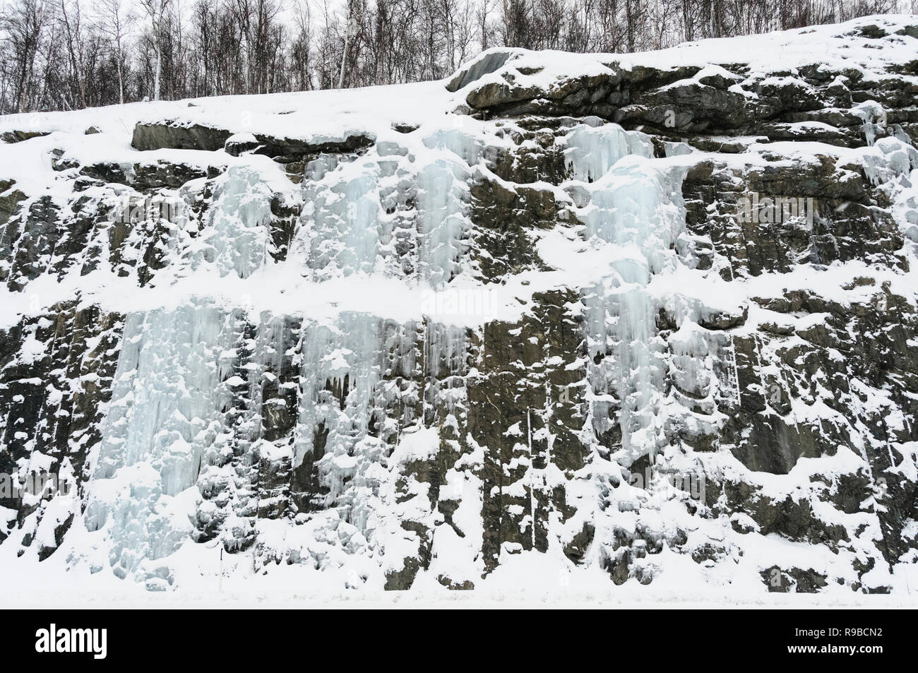 Cascata ghiacciata con ghiaccioli, le rocce e la neve vicino a Tromsö nelle regioni artiche della Norvegia Foto Stock
