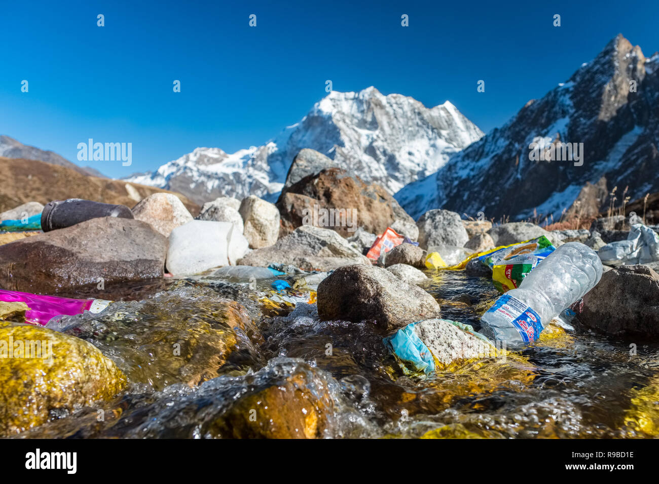 Di plastica e di altri rifiuti da un trekker's Lodge gettati in un flusso glaciale in Nepal Himalaya Foto Stock