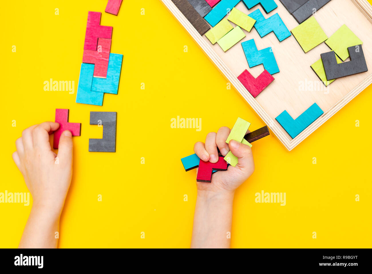 Tangram su sfondo giallo e i bambini le mani. Lay piatto Foto Stock