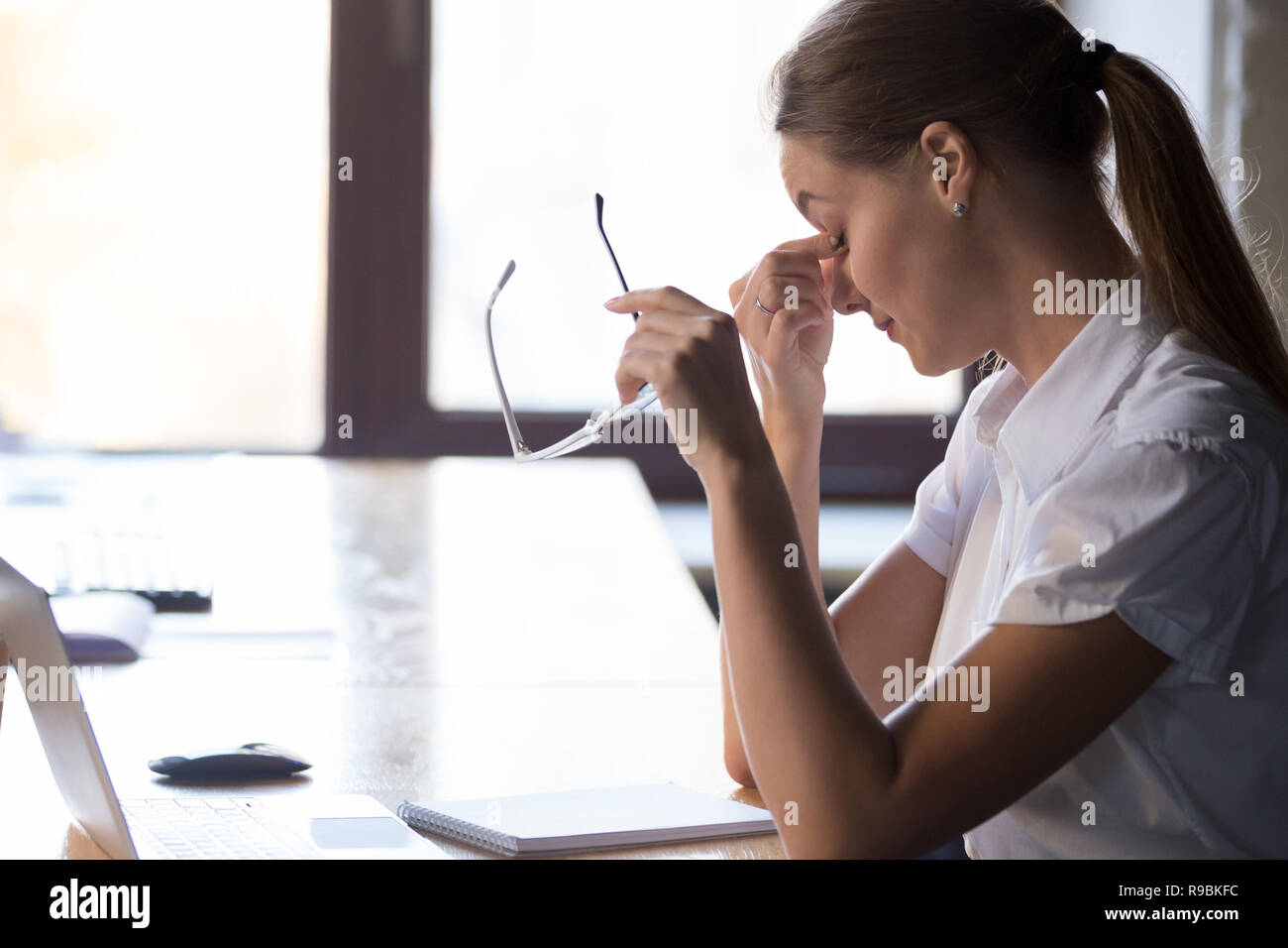 Giovane donna stanchi studente lavoratore decollare occhiali, occhi fatigu Foto Stock