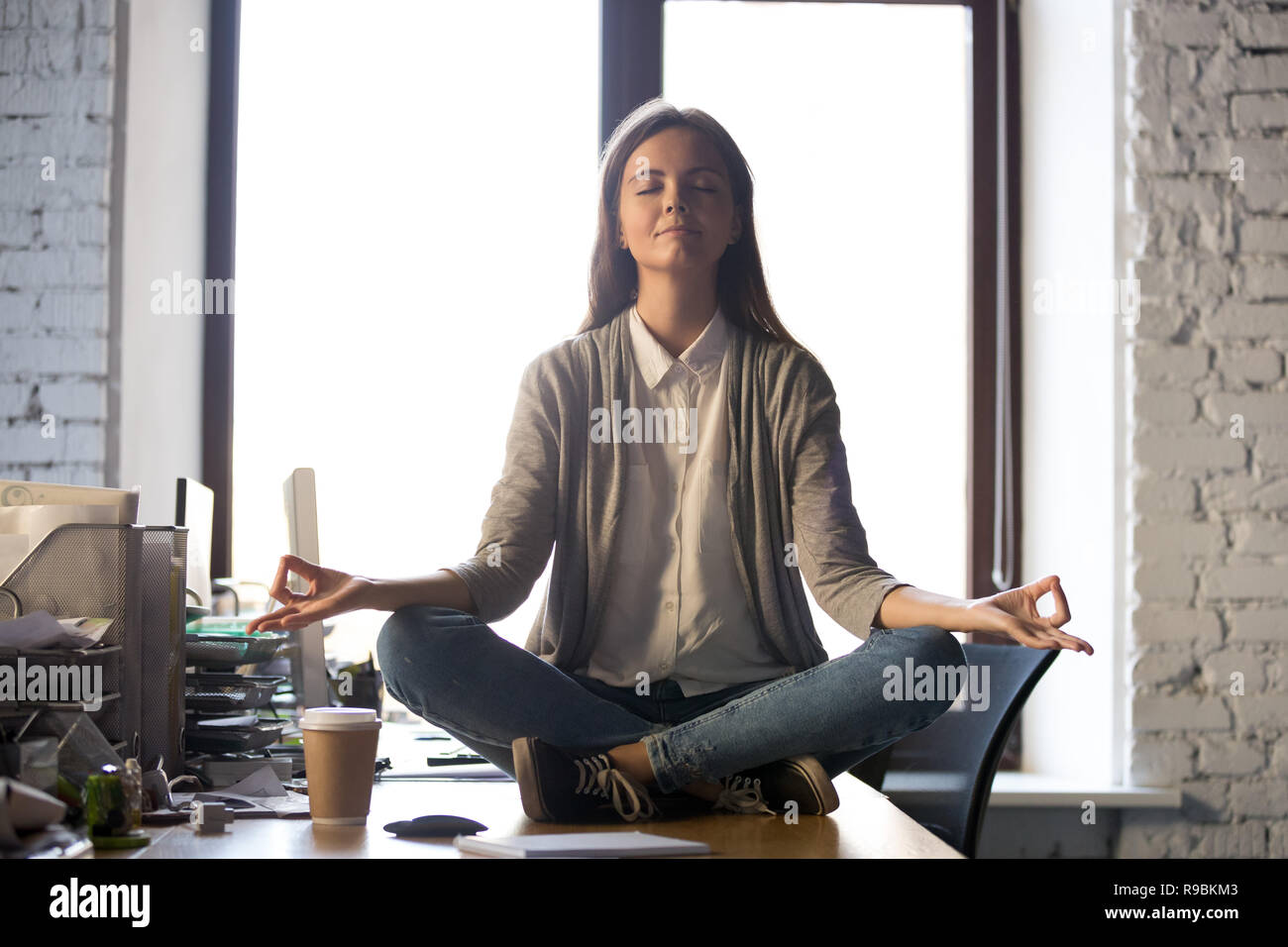 Serena tranquillità business donna sedersi sulla scrivania in ufficio la meditazione Foto Stock