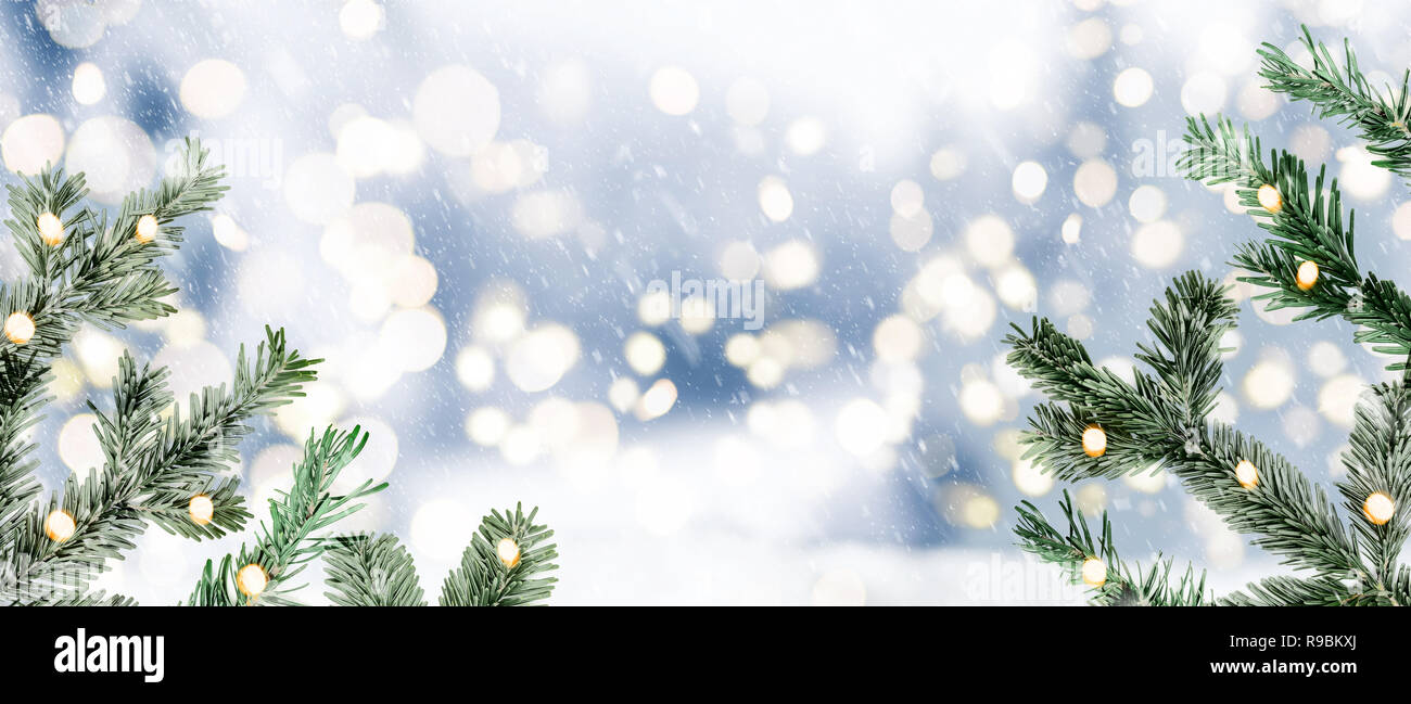 Festive sfocata nevoso inverno sfondo di Natale con ramoscelli di abeti e luci circolari Foto Stock