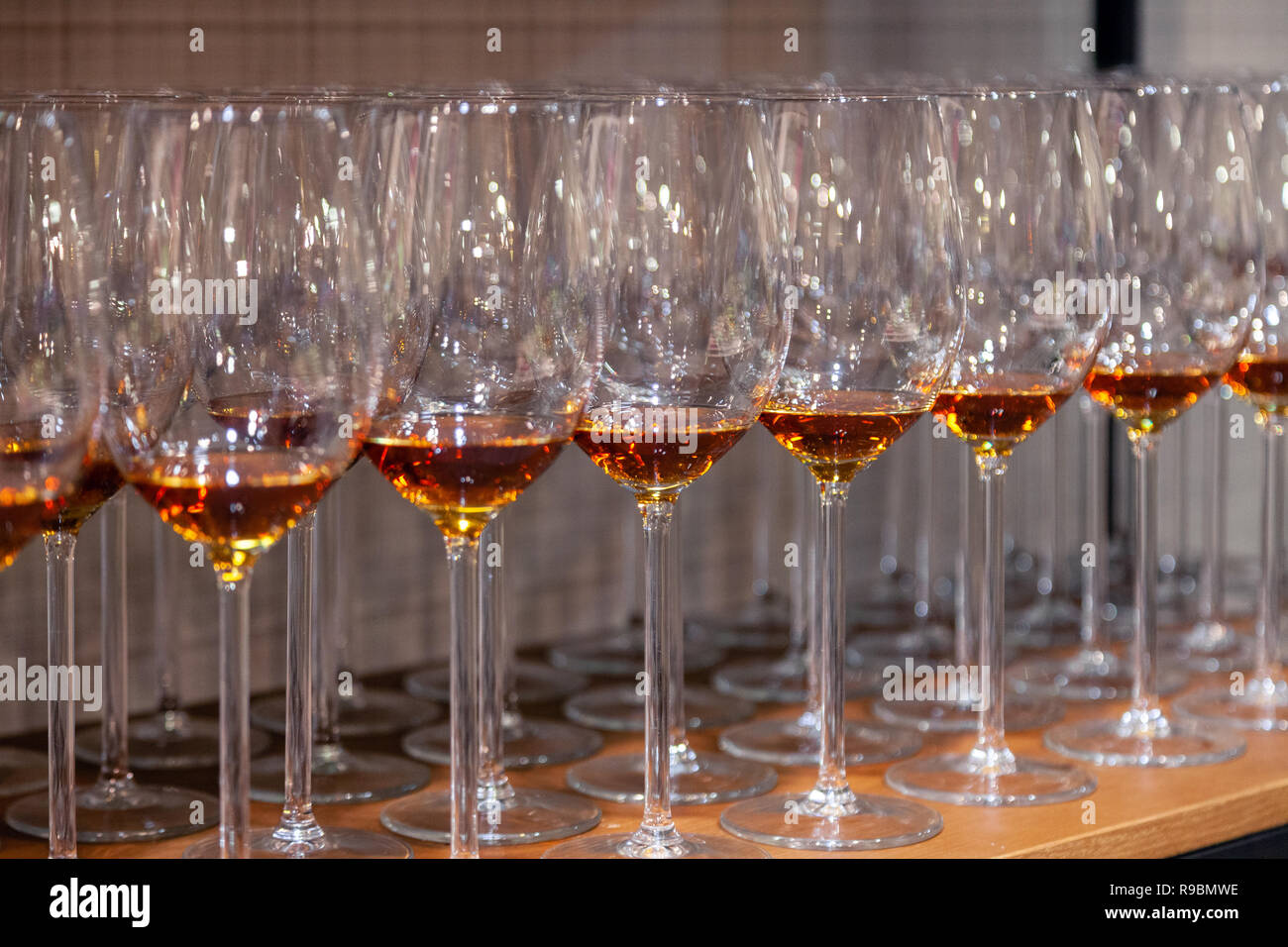 Molti in cristallo trasparente bicchieri di vino con il cognac stand in fila sul marrone ripiani in legno del rack. Vista laterale. Concetto di degustazione distillati: whi Foto Stock