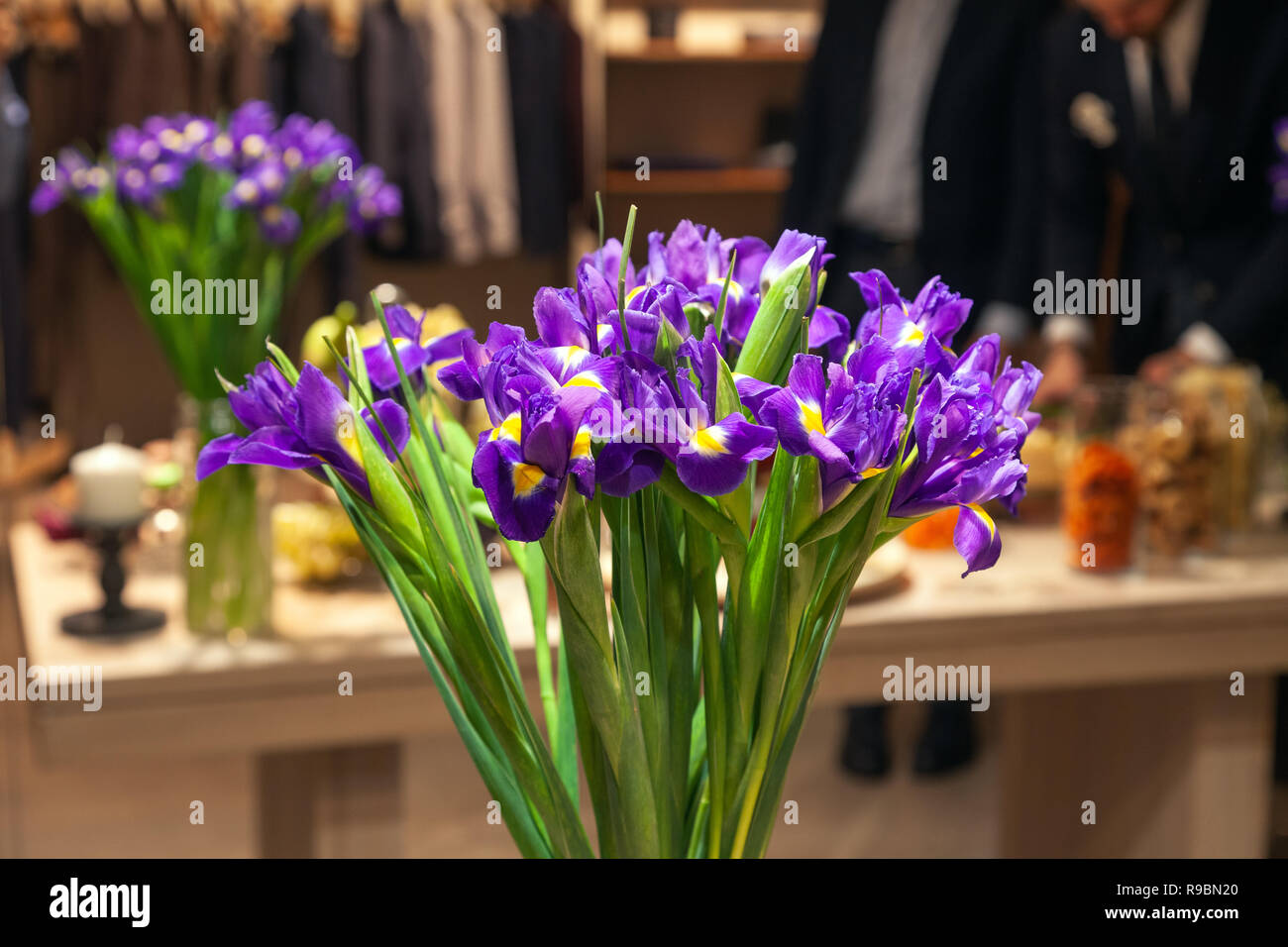 Closeup bouquet di fiori freschi iridi viola con dettagli giallo stand in vaso di vetro. Сoncept di apertura negozio di fiori, fiori freschi di arredo per whiske Foto Stock