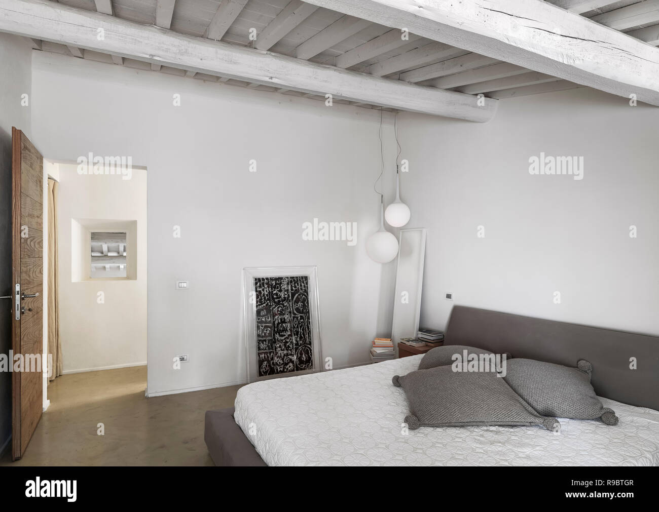 Scatti di interni di una moderna camera da letto con soffitto in legno e pavimento in resina Foto Stock