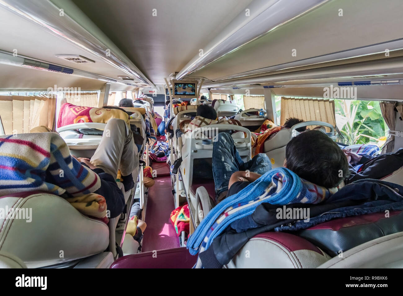 Reportage girato dell uomo guardando la TV a lunga distanza sleeper bus in Asia, di giorno Foto Stock