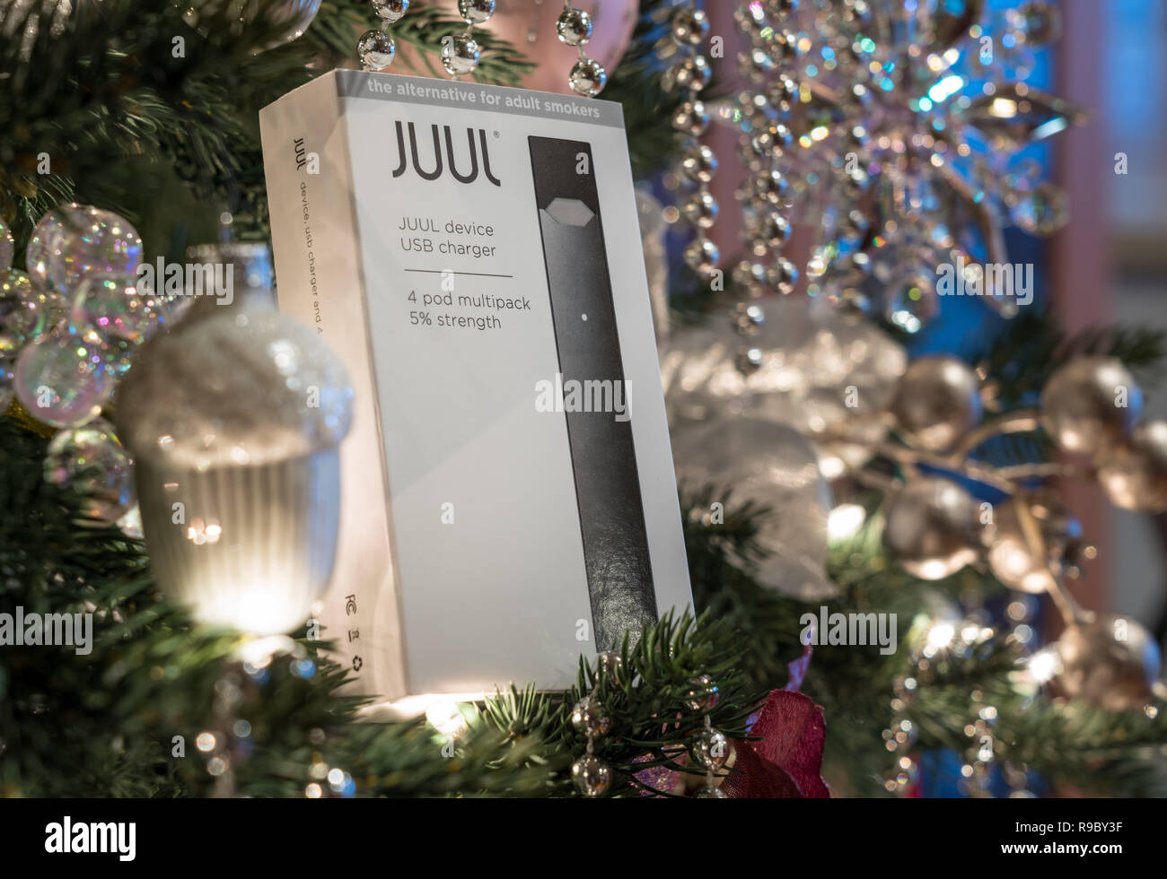 Casella azienda JUUL dispensatore di nicotina e baccelli su albero di Natale Foto Stock