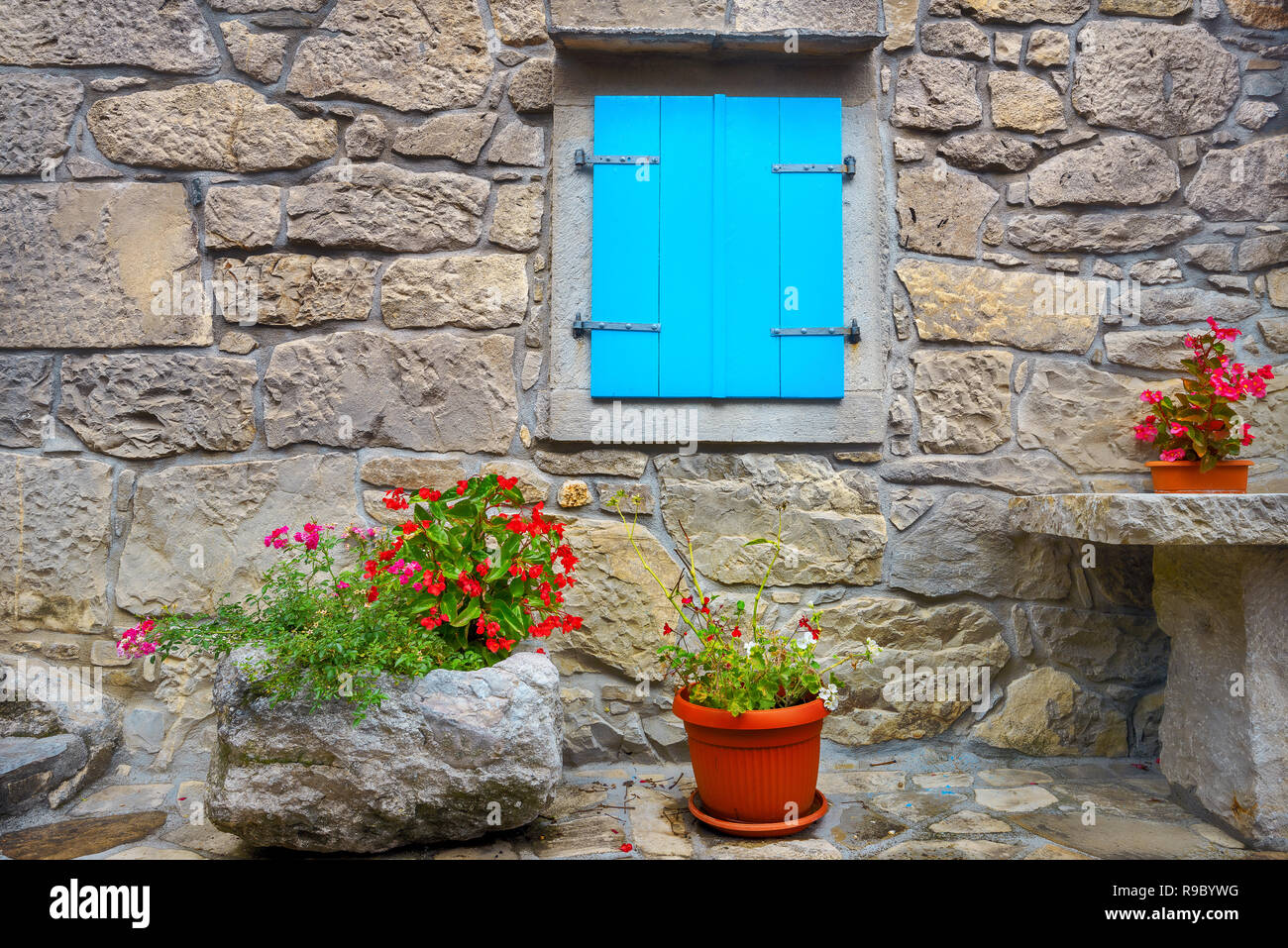 La facciata della vecchia casa con muro di pietra e di legno finestra blu, decorato fiori in vasi da fiori. Hum, Croazia Foto Stock