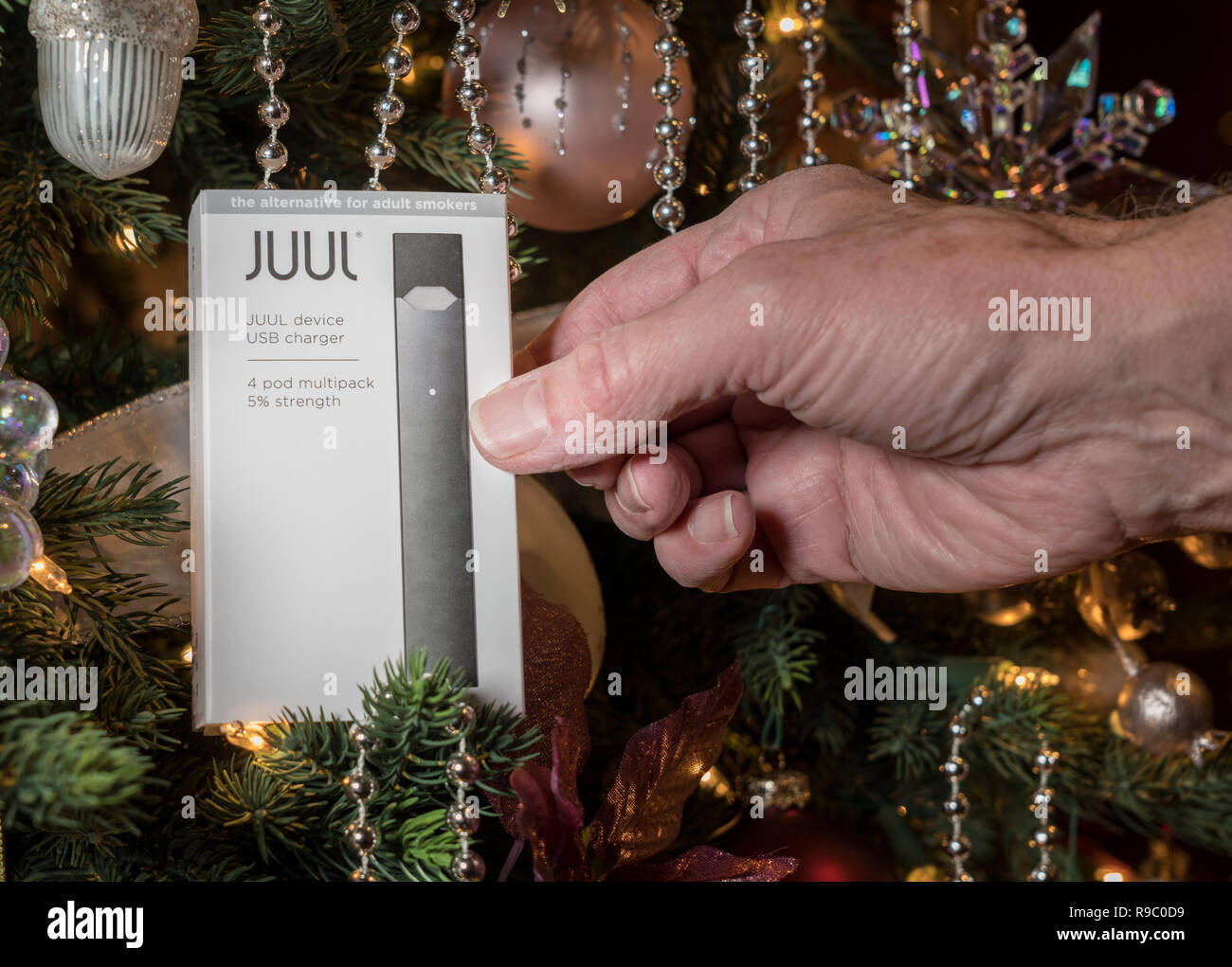 Casella azienda JUUL dispensatore di nicotina e baccelli su albero di Natale Foto Stock