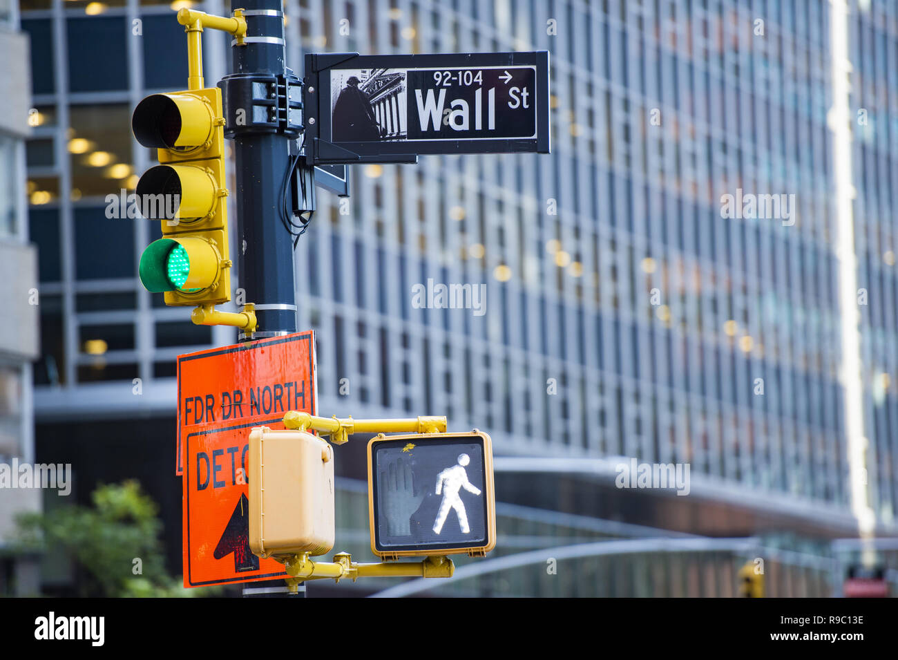 Wall street sign in primo piano e un enorme edificio sfocata in background in Manhattan. Foto Stock