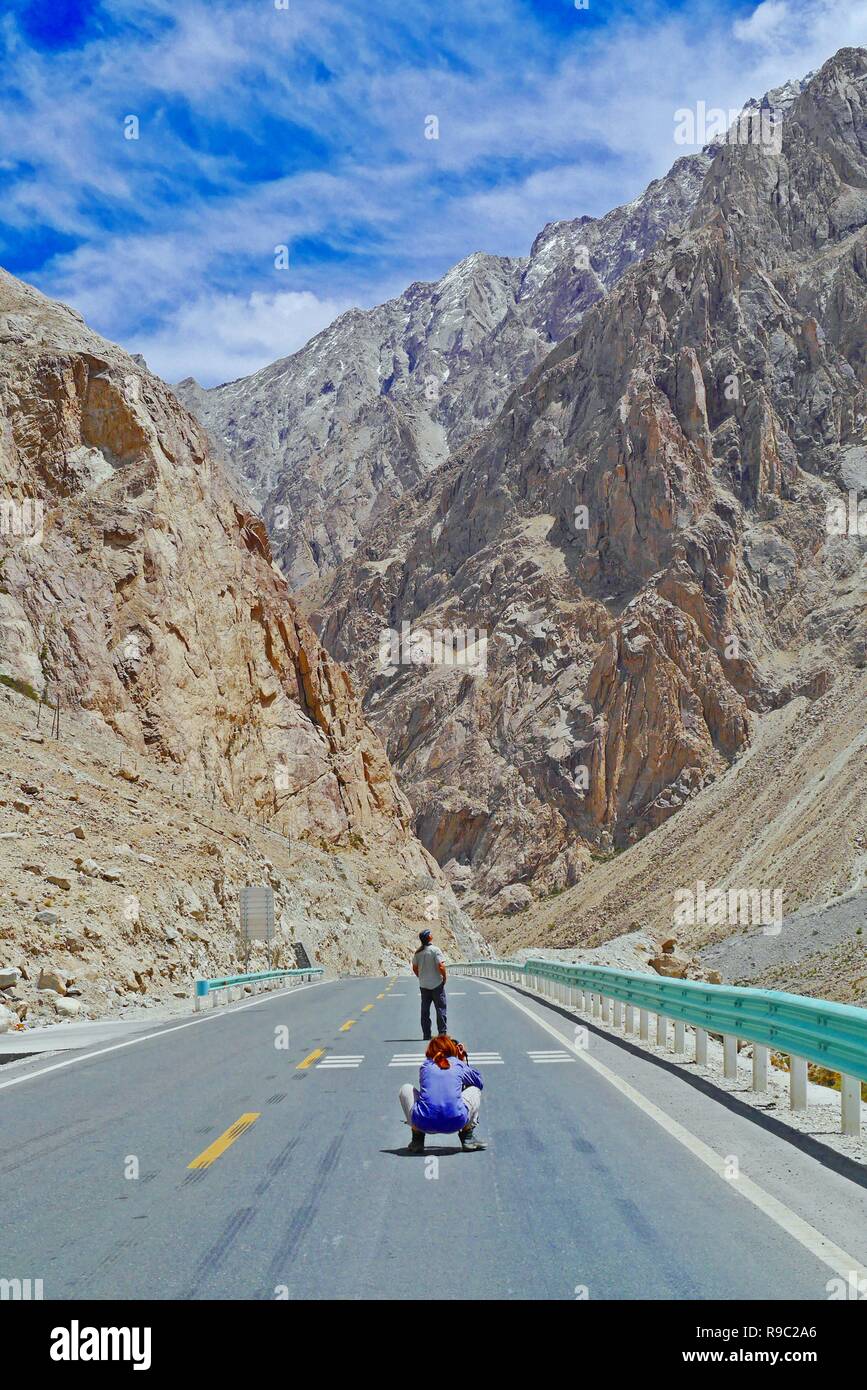 Turisti viaggiano lungo la Karakoram Highway nello Xinjiang Uyghur Regione autonoma, Cina, con lo splendido paesaggio di montagna della Valle dello sfondo. Foto Stock