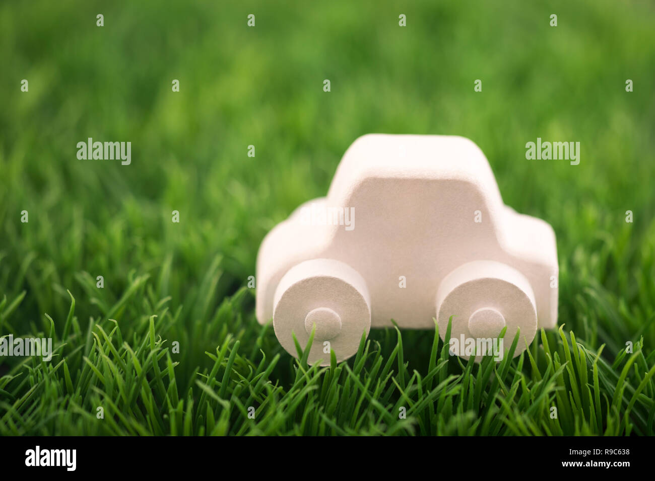 Auto giocattolo sul prato verde. Guida Ecologica concetto Foto Stock