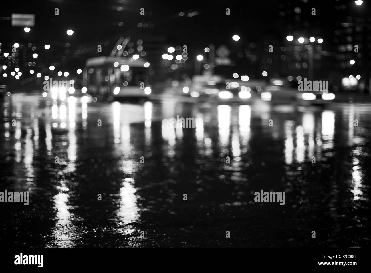 Rainy city road durante la notte con le luci di riflessione. Abstract defocalizzata immagine in bianco e nero Foto Stock