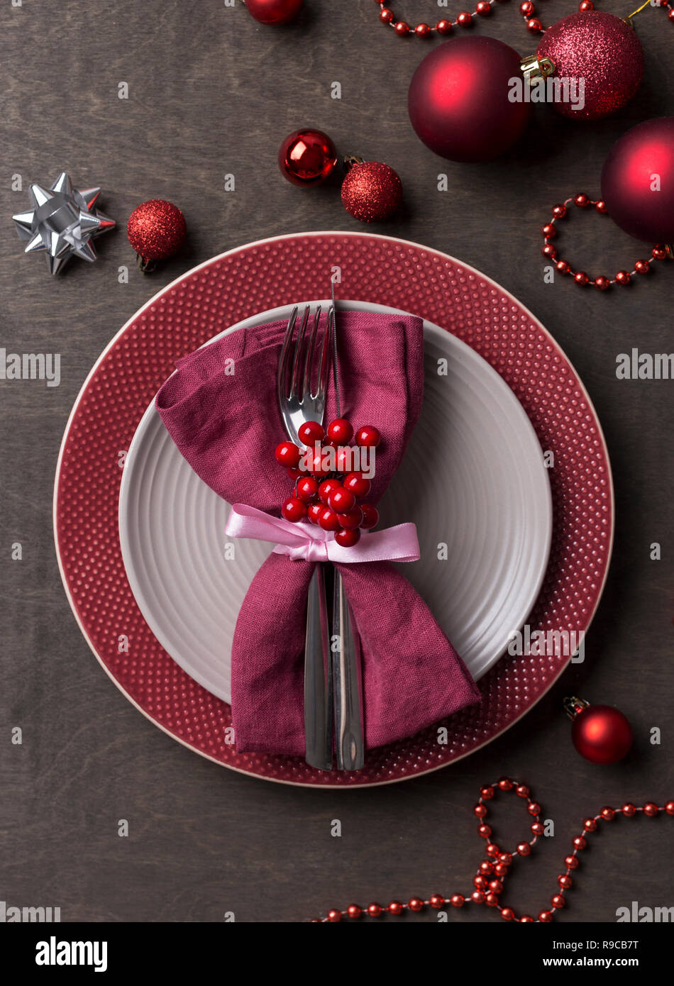 Tavola di Natale posto impostazione con vuoto grigio e rosso piastre, con decorazioni di festa di bacche e di giocattoli di Natale in un tavolo di legno. Natale Xmas nuovo Foto Stock