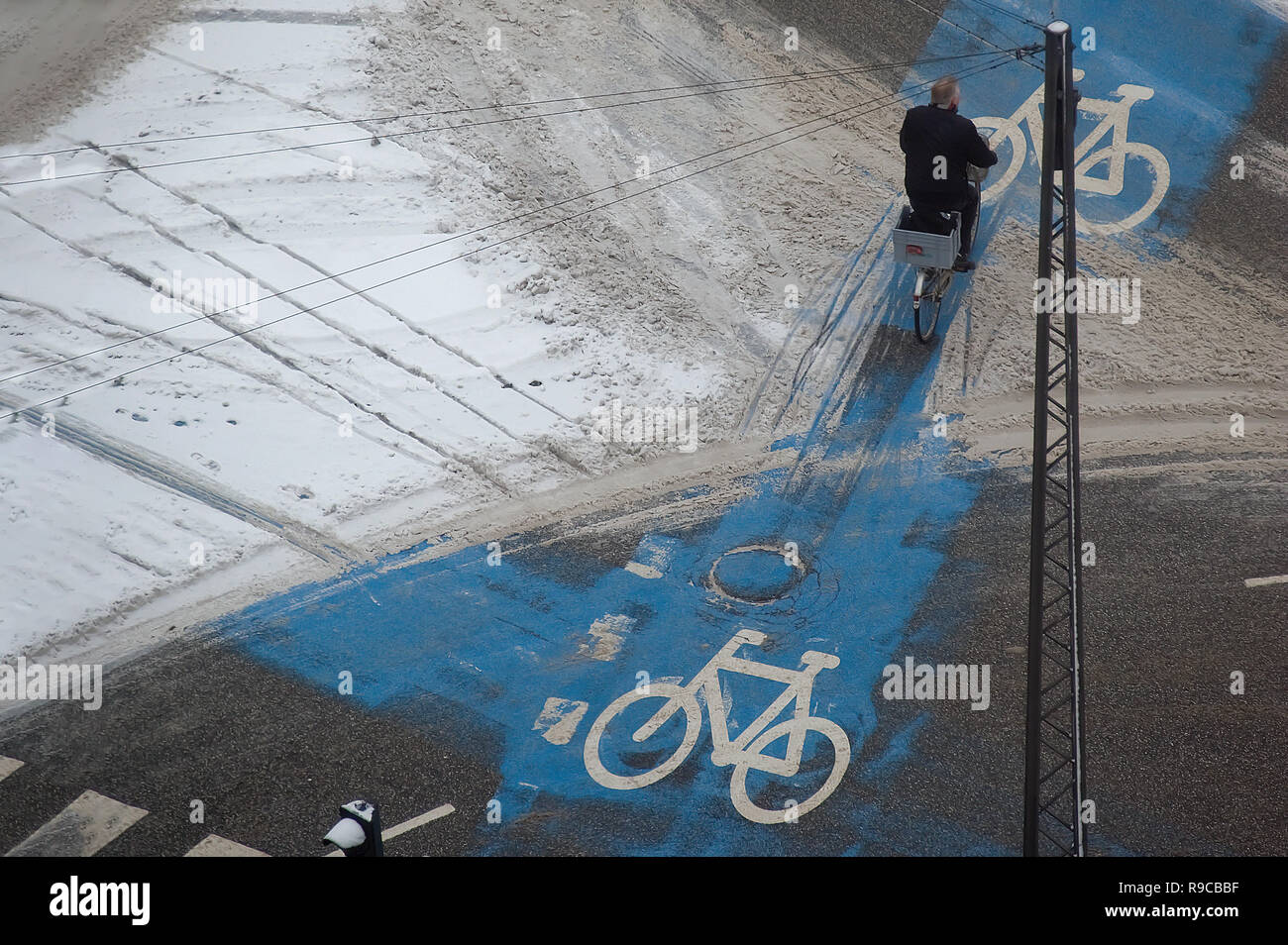 Vista superiore dell'uomo corse in bicicletta in parte coperta di neve Bici-lane a metà inverno, Copenhagen, Danimarca. Foto Stock