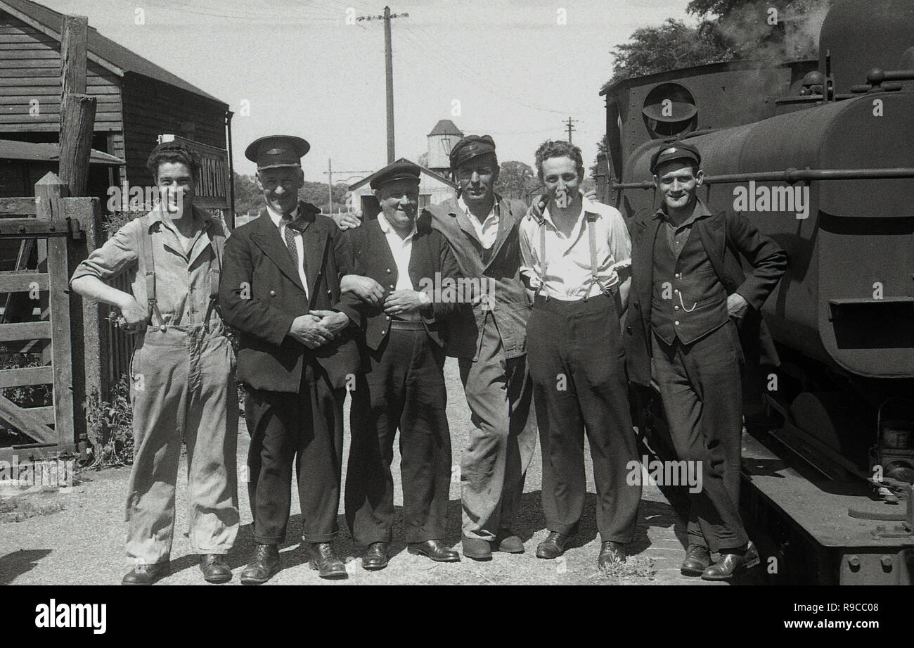 195, storici British Railways lavoratori compresi i macchinisti,le protezioni e la stazione master, di stare in piedi insieme all'esterno accanto a un treno a vapore per una foto di gruppo. Foto Stock