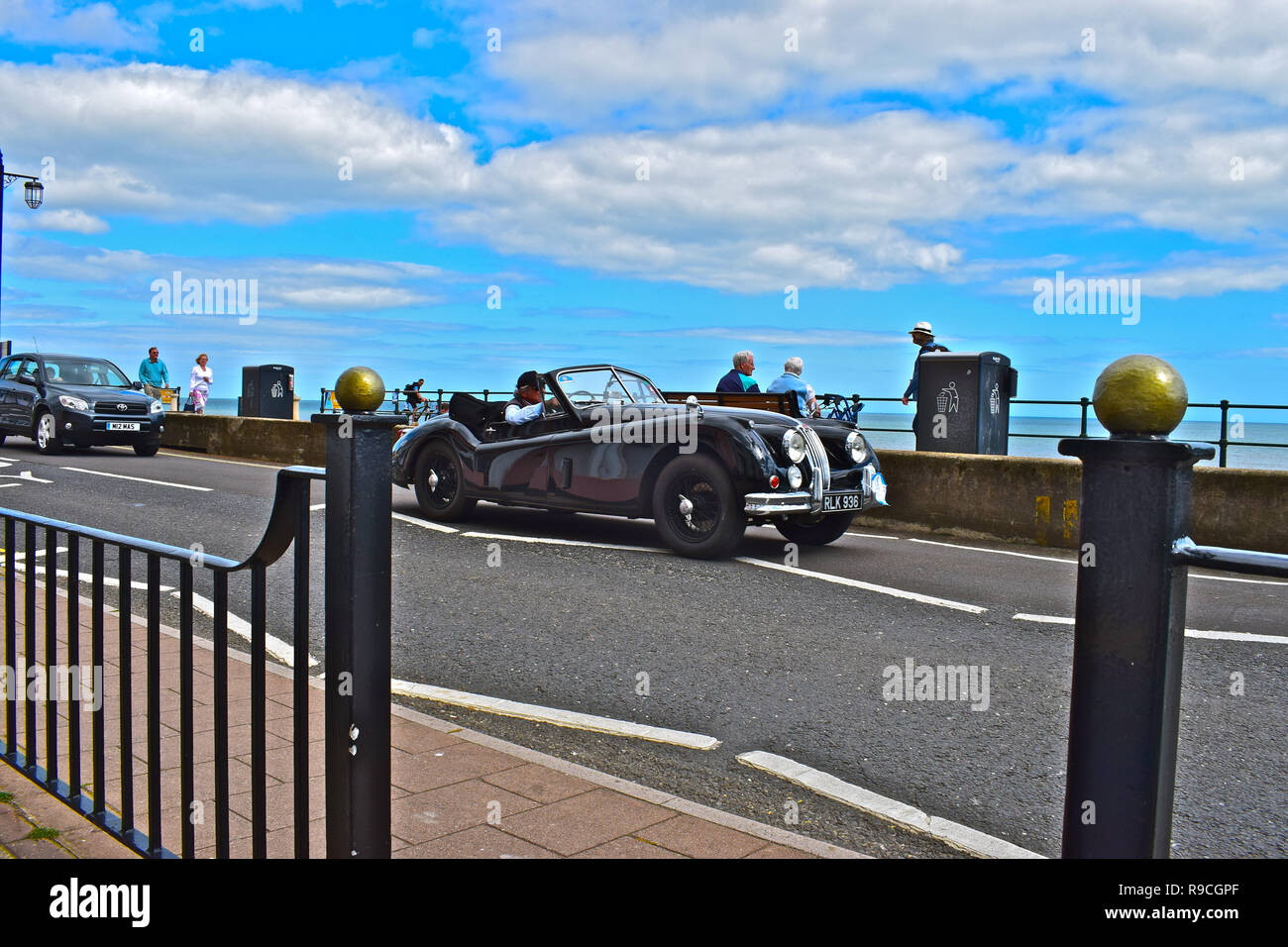 Un classico Jaguar XK120 auto sportiva trascina lungo l'esplanade a Sidmouth, pur prendendo parte al Round Britain unità costiere 12-29giugno 2017. Foto Stock