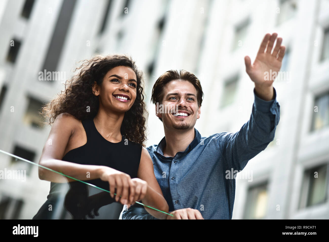 Felice coppia internazionale hanno una conversazione in città. Razza mista donna e uomo caucasico. Foto Stock