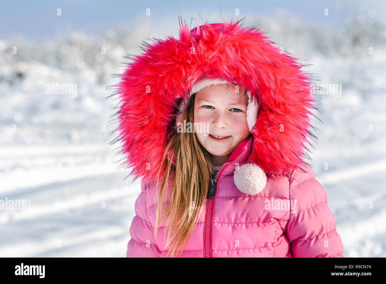 Ritratto di una bambina nella neve su una soleggiata giornata invernale. Foto Stock