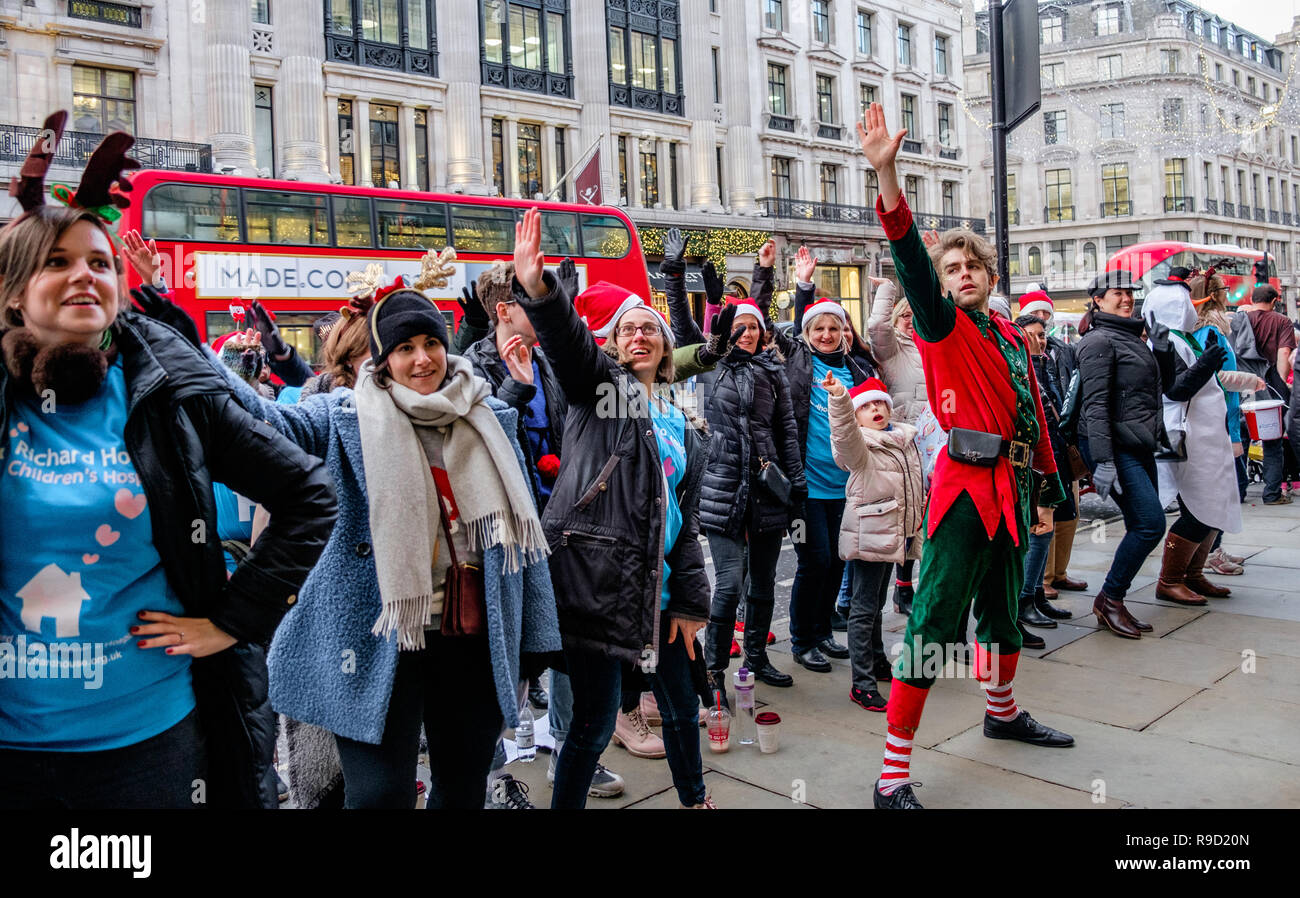 Hamleys' Elf Mike Rogers danze improvvisate con volontari da Londra i bambini ospizio Richard House, su Regent Street. Londra. Natale 2018 Foto Stock