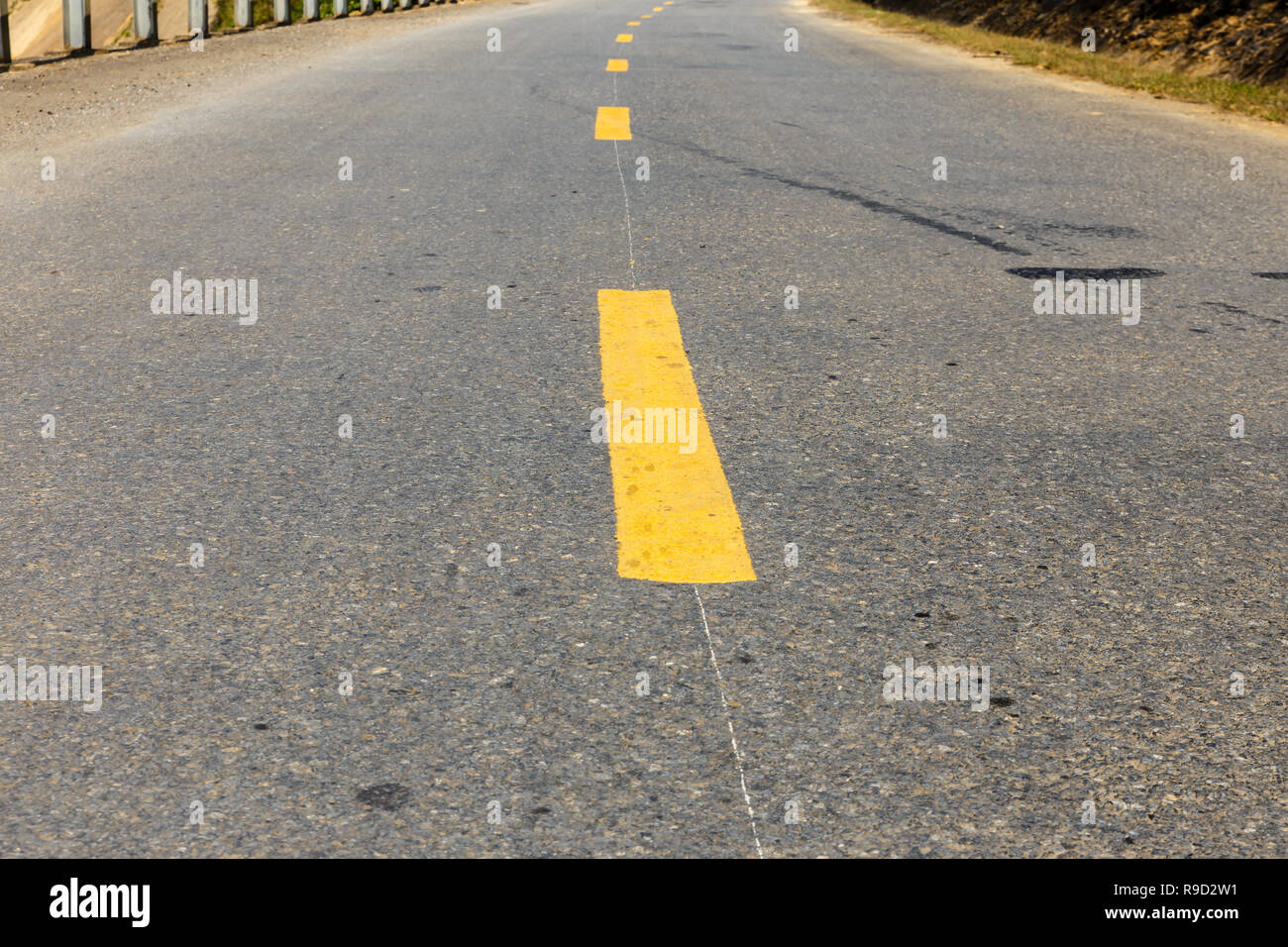 Giallo linea tratteggiata sulla strada asfaltata Foto Stock