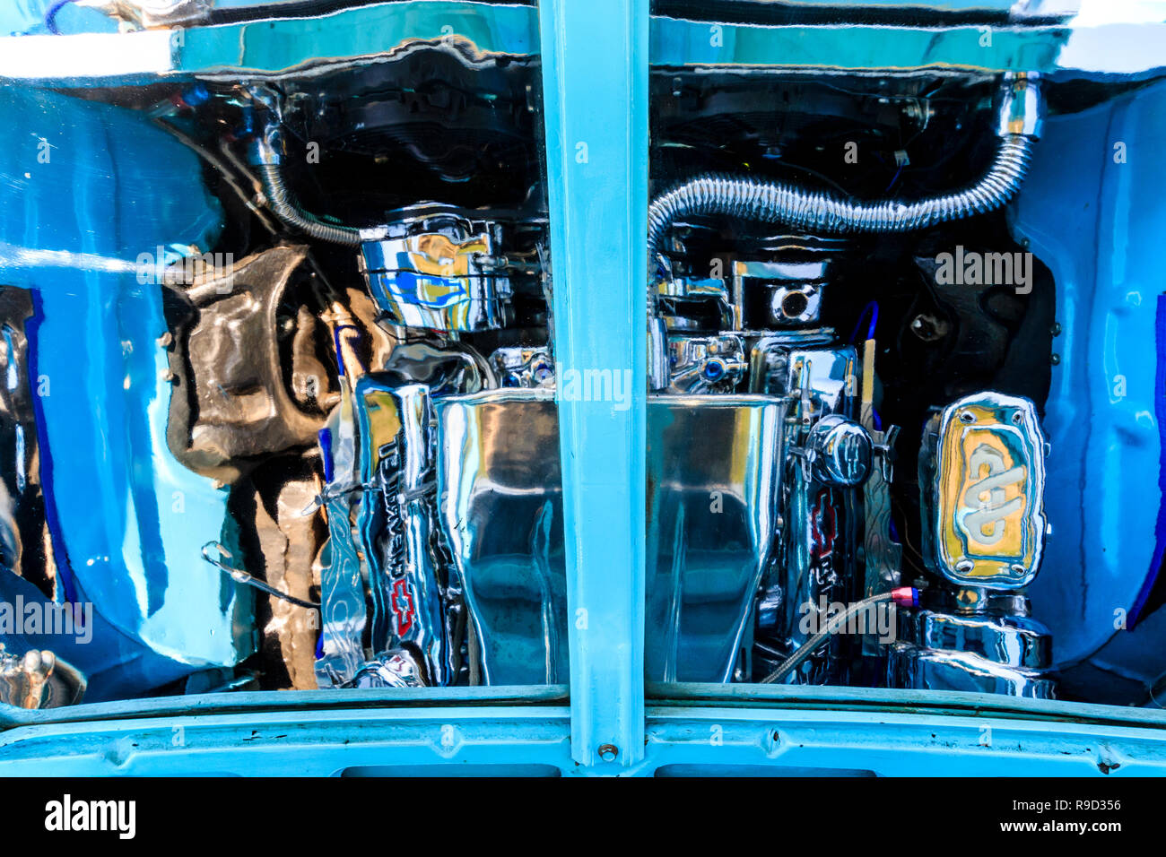 1957 Chevrolet Bel Air auto. La riflessione del motore personalizzato visto sulla parte inferiore del altamente lucido cofano, il cofano della macchina. Luce di colore blu. Foto Stock