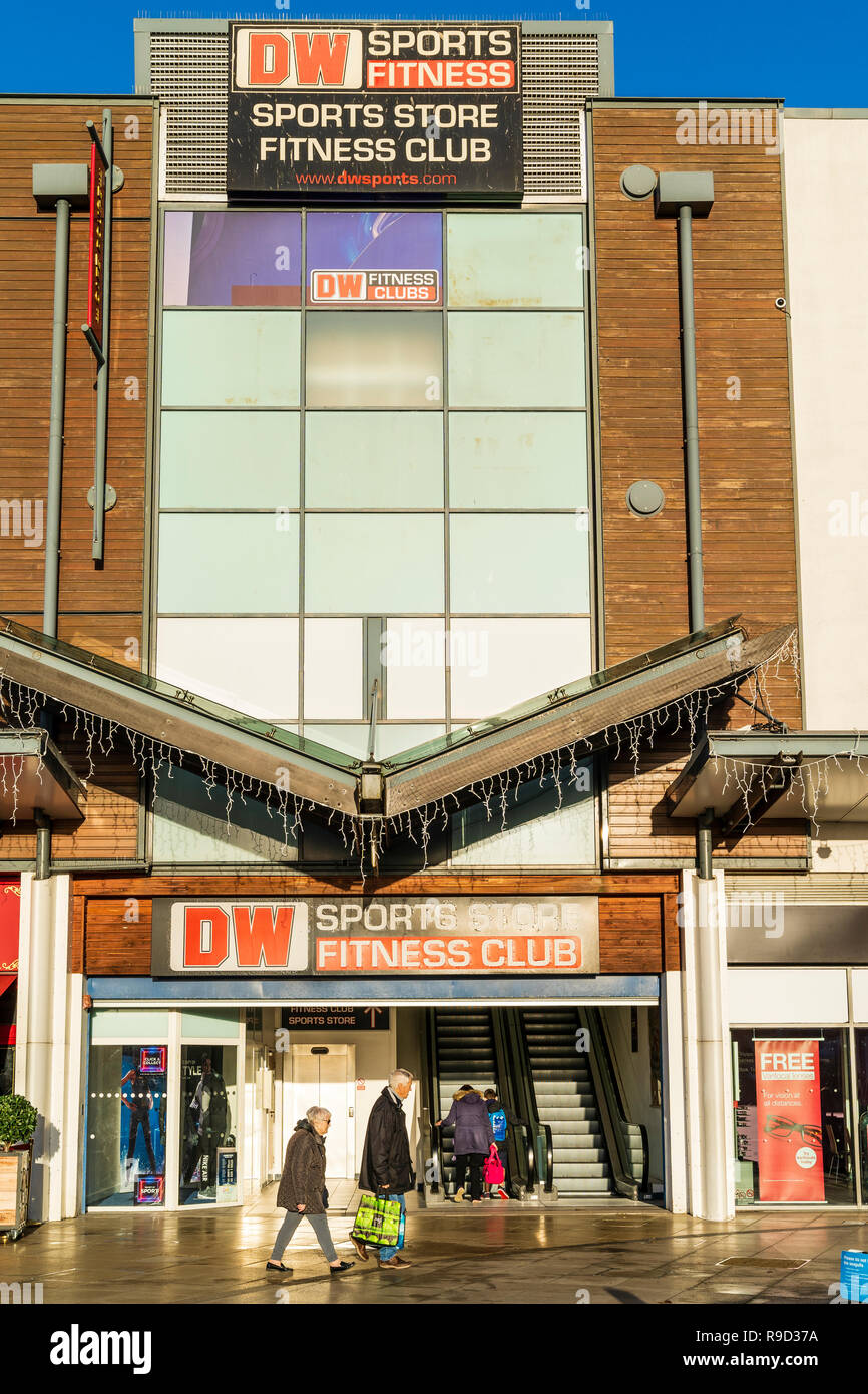 Westwood Cross Shopping Centre, Broadstairs. DW negozio di sport e fitness club ingresso con una vecchia coppia camminando passato. Foto Stock