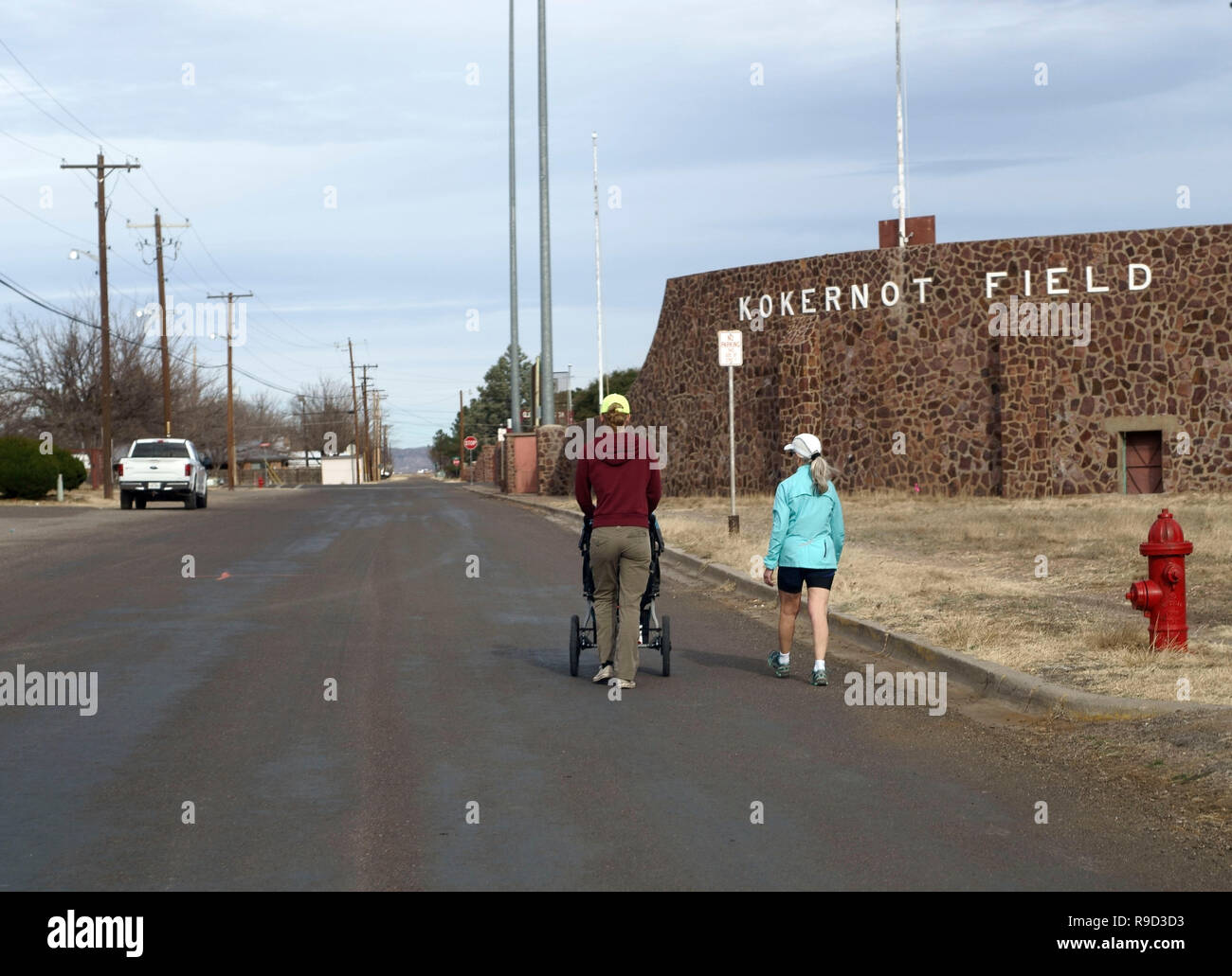 Due donne di camminare un bambino in un passeggino in un vuoto di street in Alpine, Texas Foto Stock