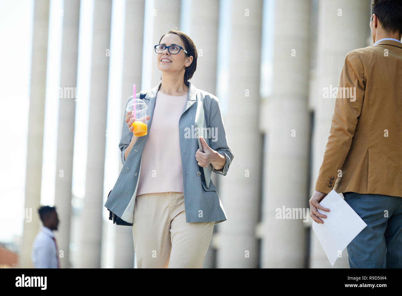 Sorridente business lady camminare vicino a edificio per uffici Foto Stock