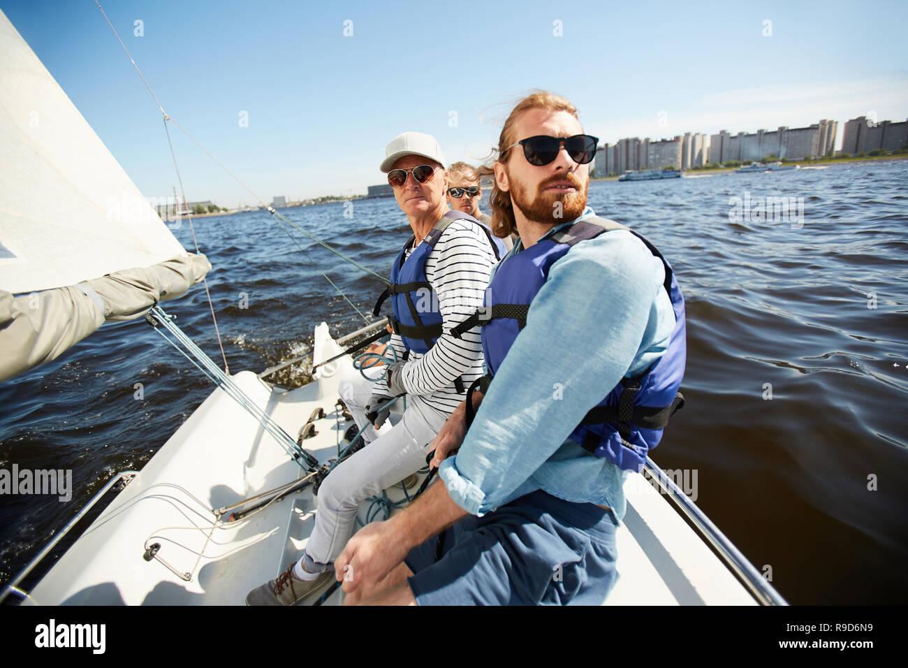 Gli uomini in giubbotti di salvataggio seduto su yacht Foto Stock