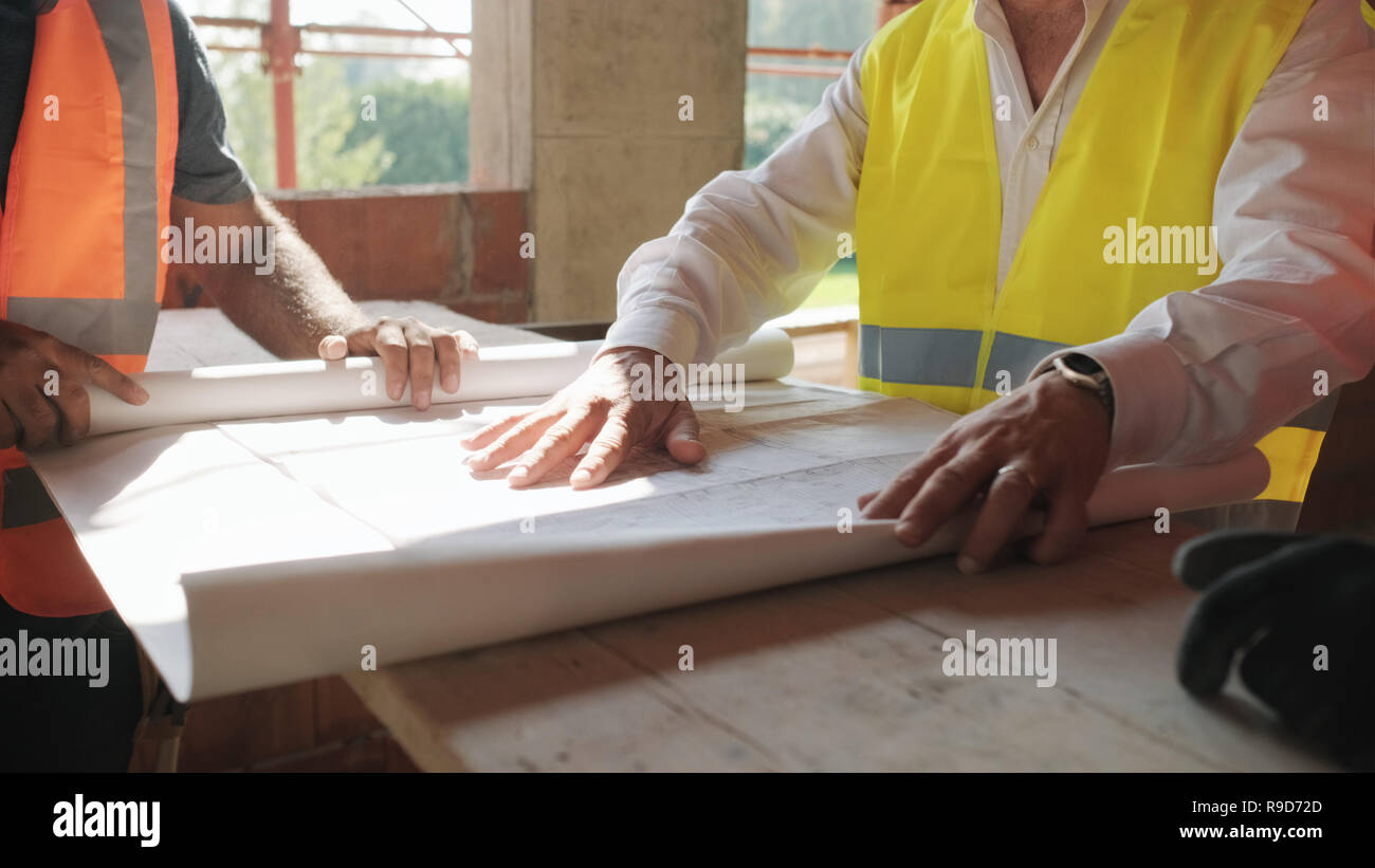 Il supervisore che mostra i piani di costruzione per i lavoratori nella nuova casa Foto Stock