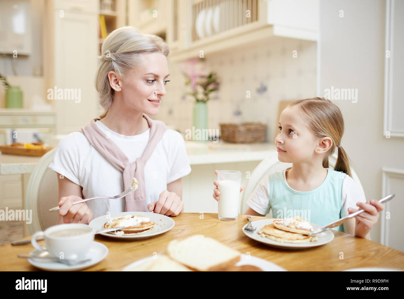 Mamma e figlia mangiare frittelle e parlare Foto Stock